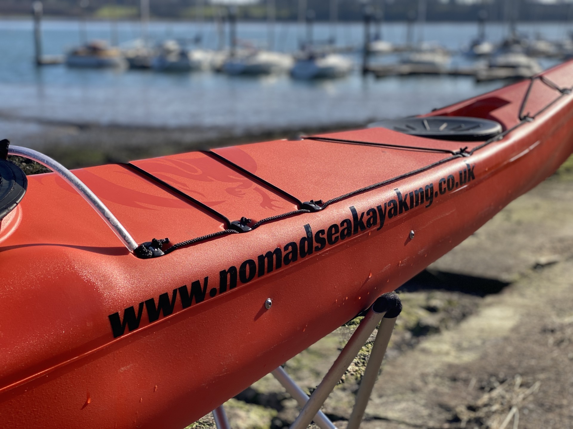 NOMAD Sea Kayaking orange sea kayak with the estuary in the background.