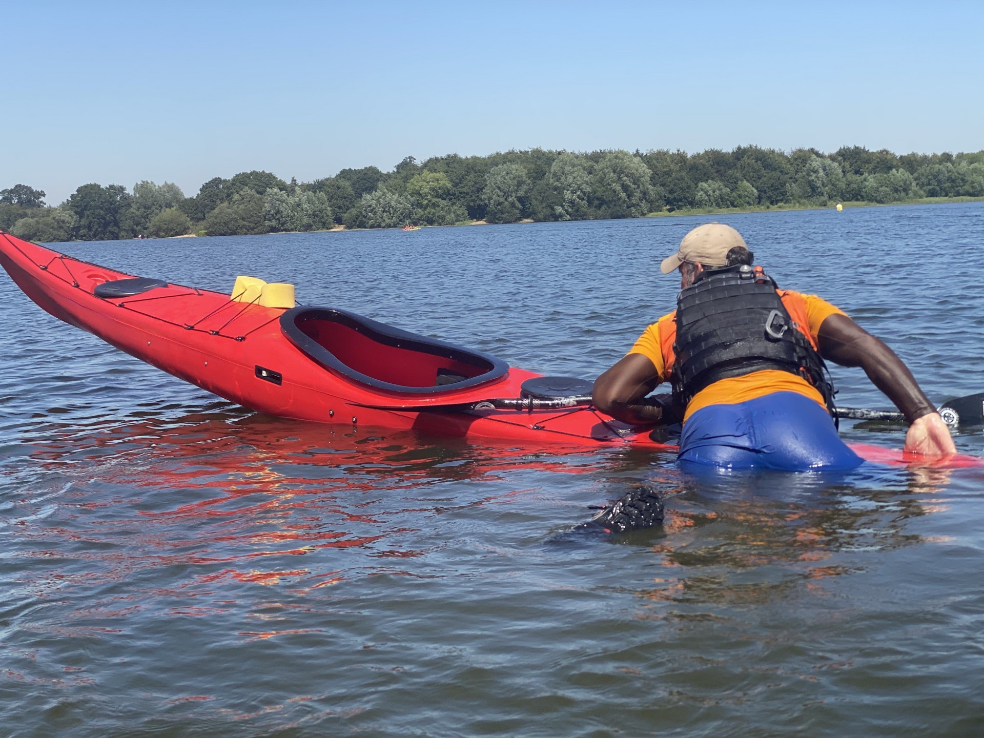 A paddler climbing onto the rear of a kayak whilst doing a self recovery during a training course