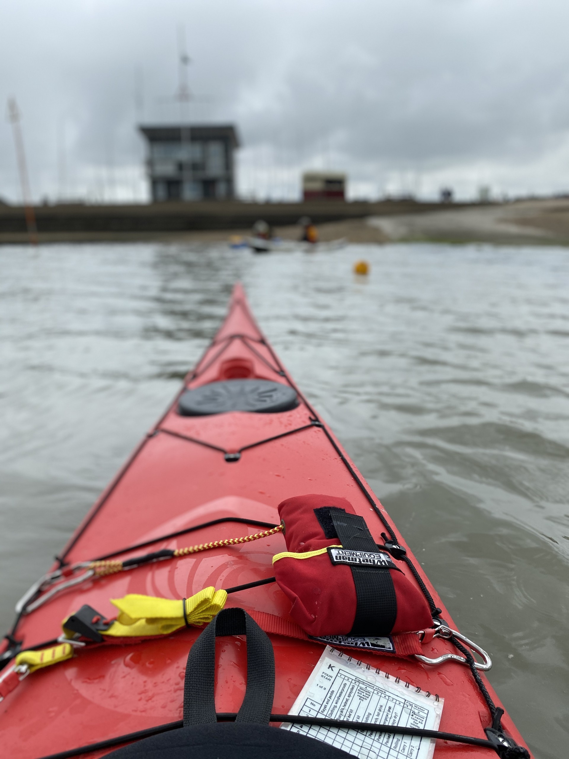 A red sea kayak on the sea with the shoreline in the distance