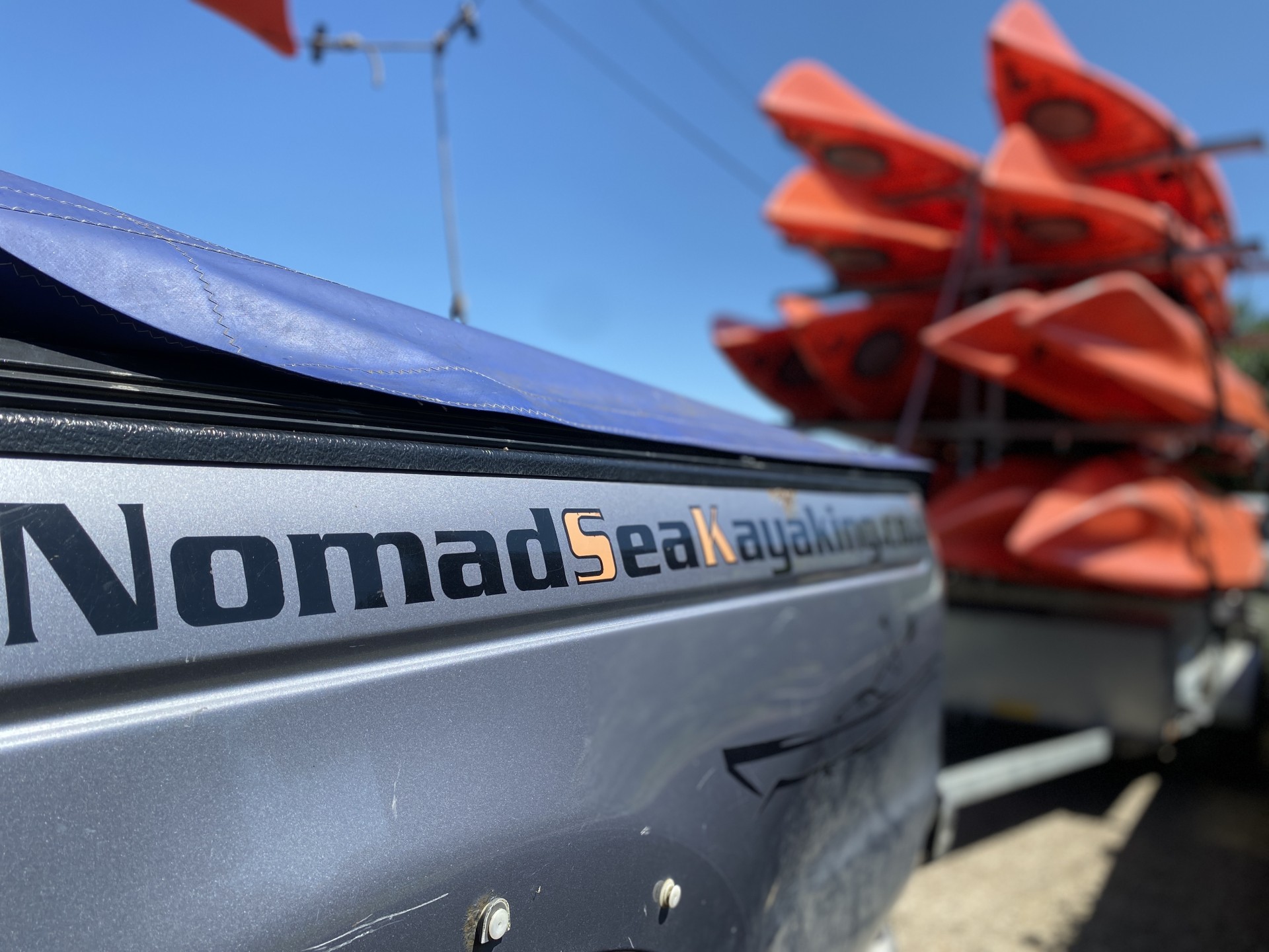 Trailer loaded with orange kayaks with NOMAD Sea Kayaking.