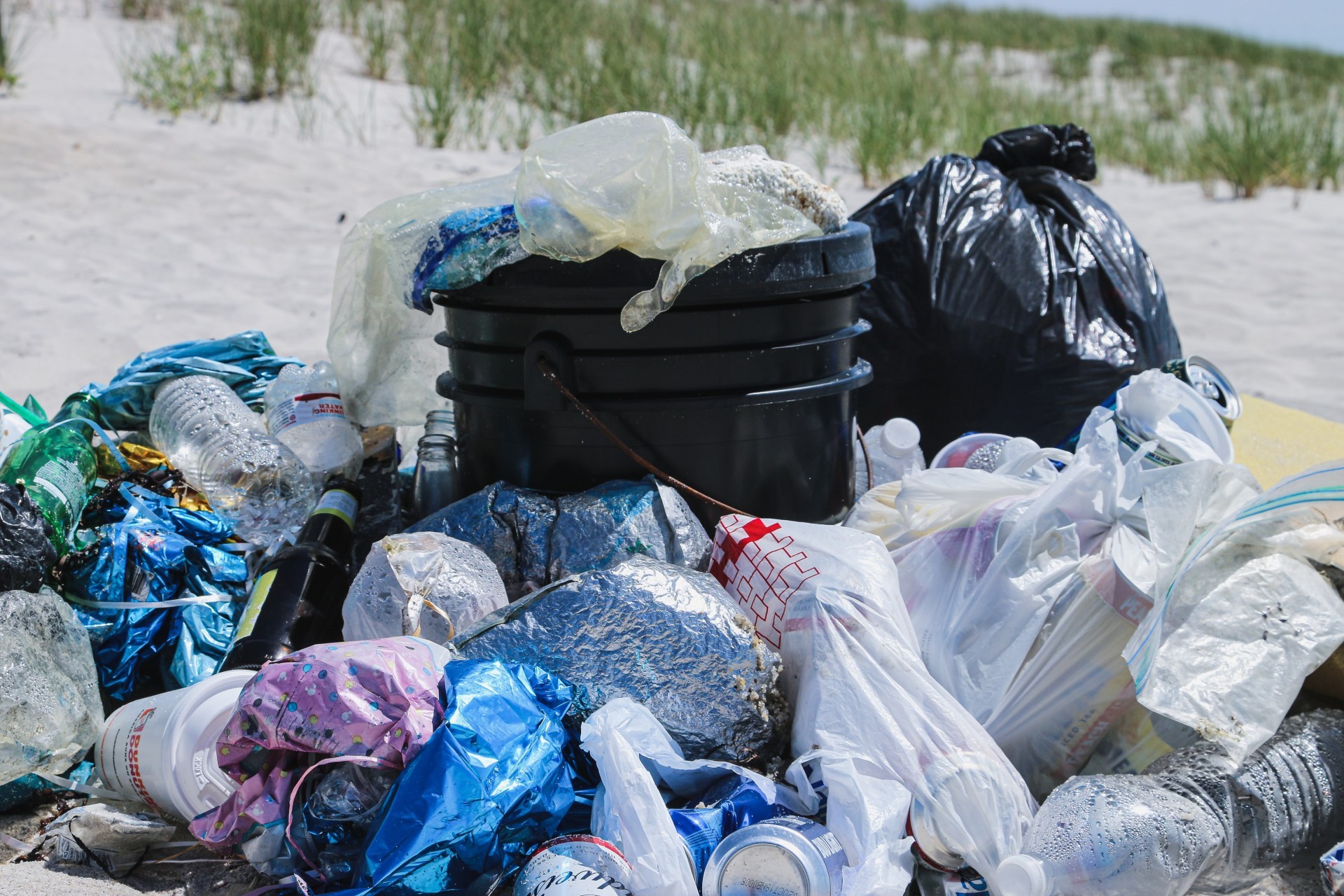 Beach refuse in bags surrounding an overflowing waste bin