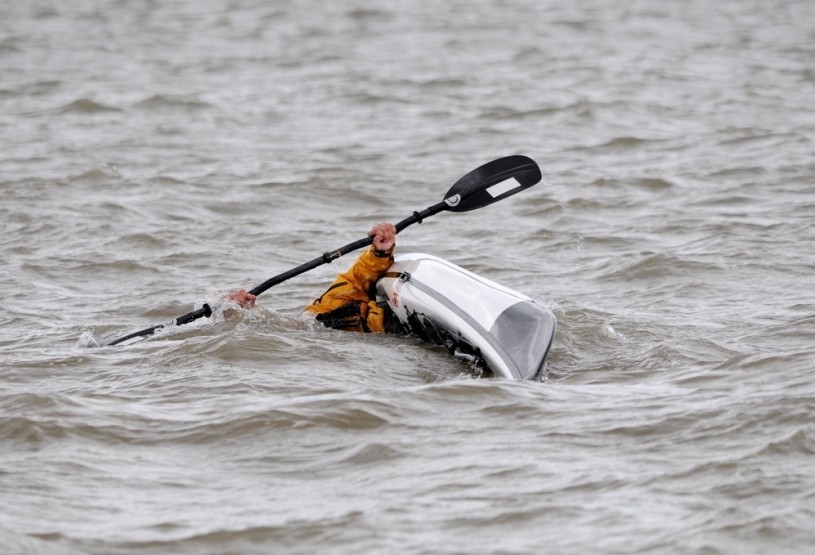 Sea kayaker doing an eskimo roll in deep water.