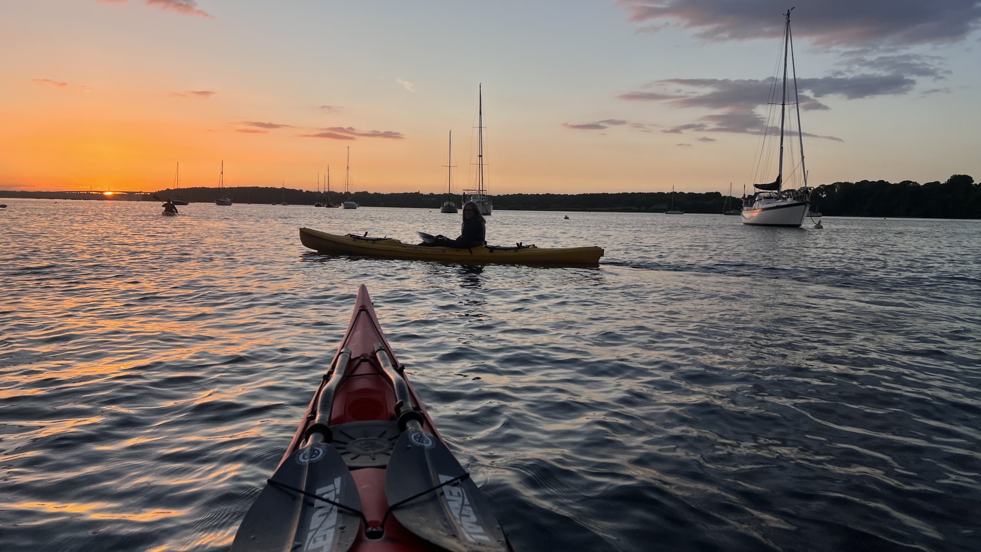 Kayaker on a sit-on-top kayak at sunset.