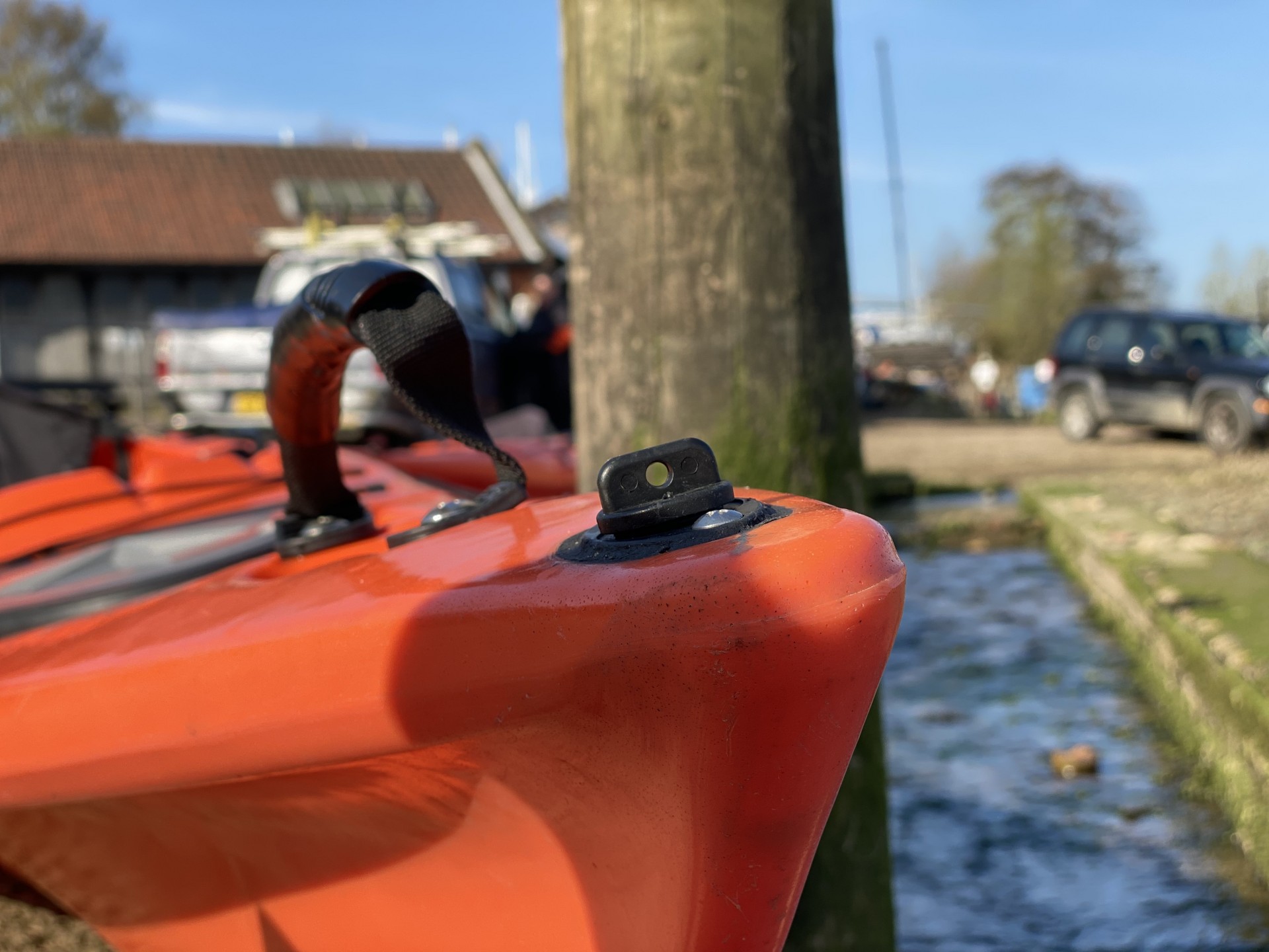 The bow of an orange sit-on-top kayak showing the drainage plug.