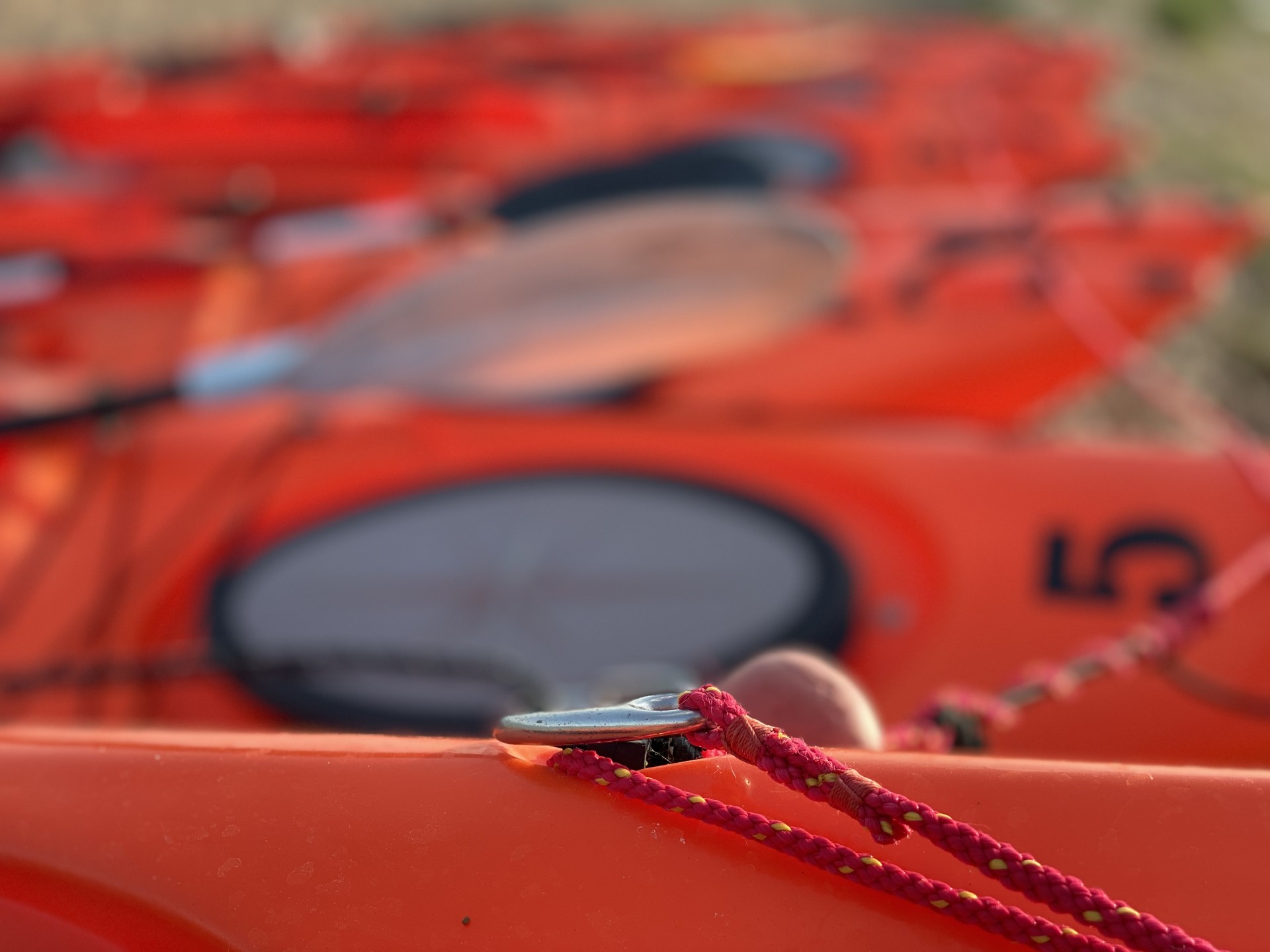 A long line of orange sit-on-top kayaks