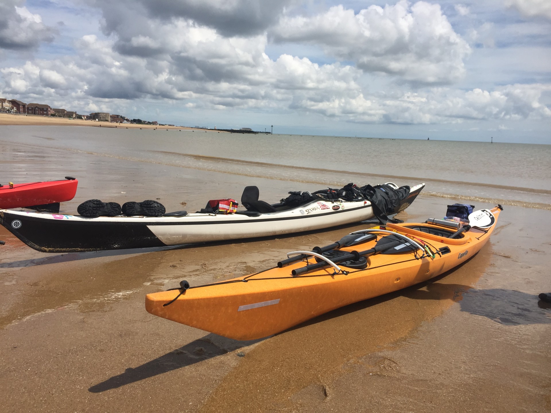 Sea kayaks on a beach in Suffolk with NOMAD Sea Kayaking.