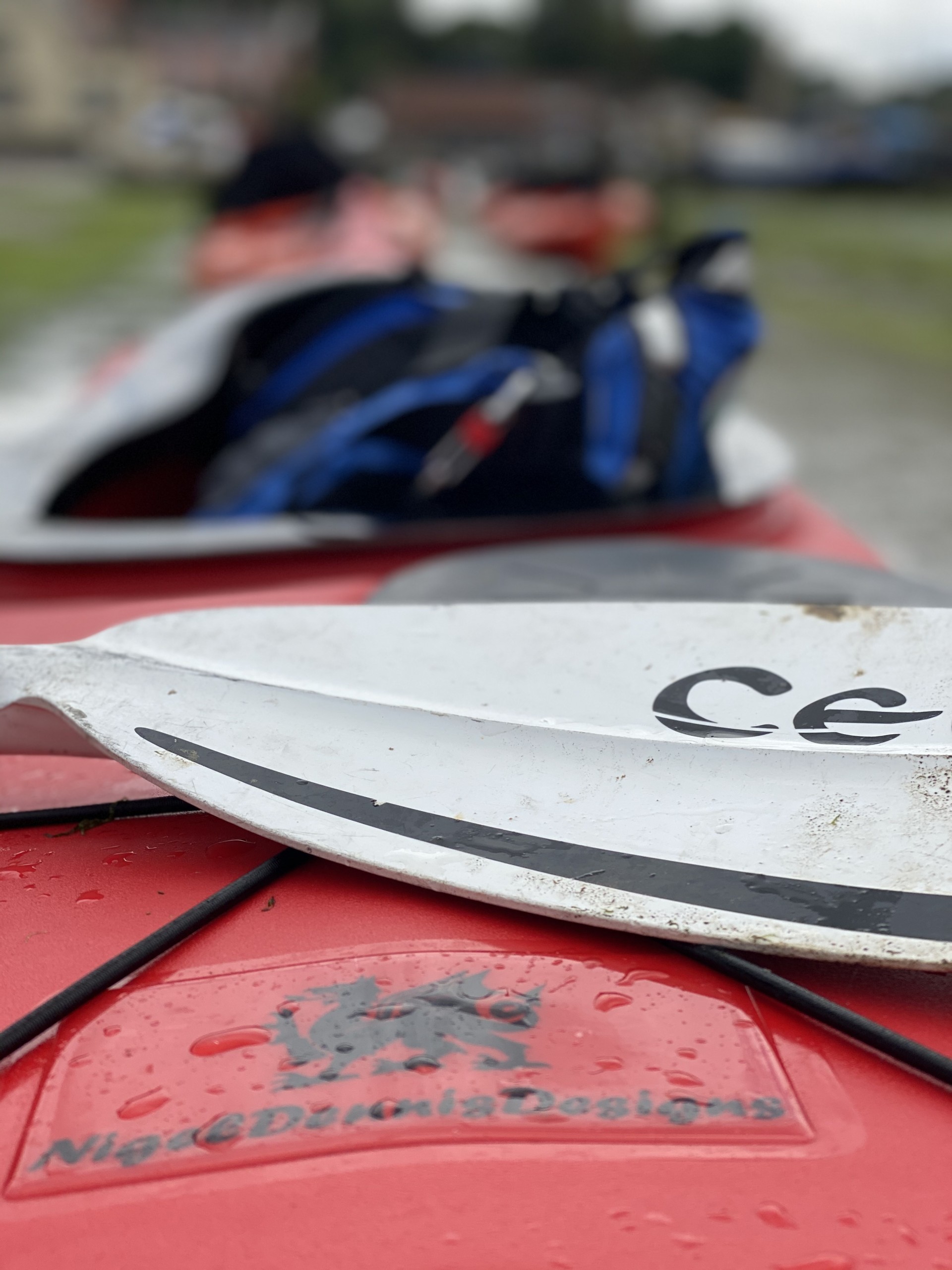 A Celtic paddle lying across the red deck of a sea kayak.