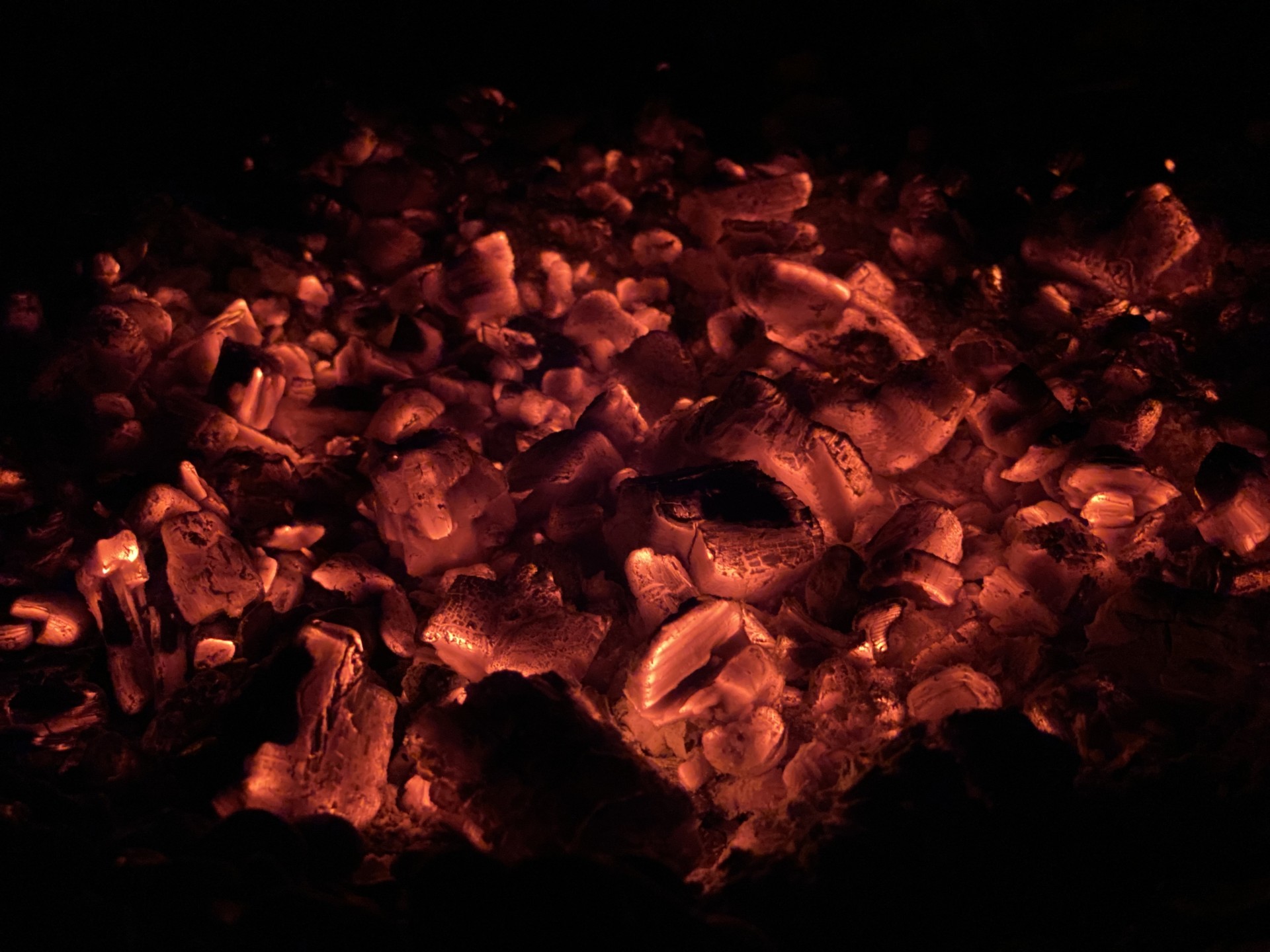 Red hot coals of a fire at night.