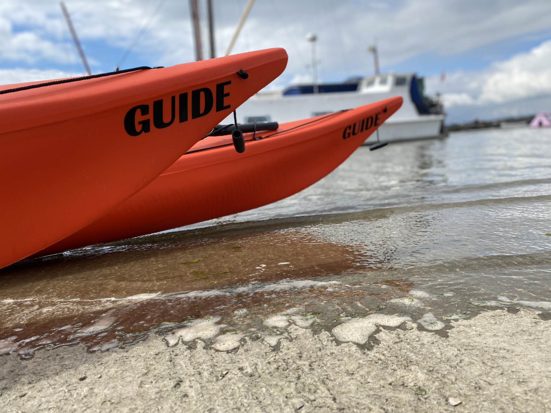 Two orange sea kayaks on the slip ready to launch.