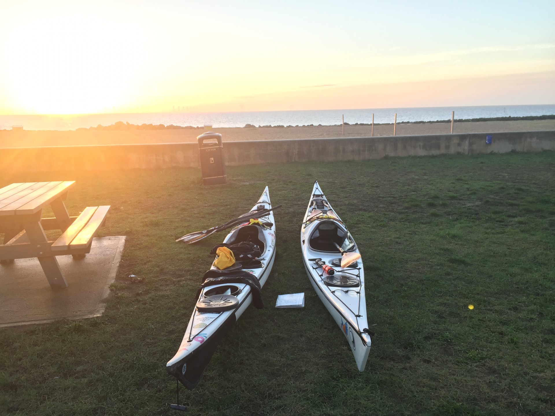 Sea kayaks on green grass with the sunrise ready for an early morning launch.