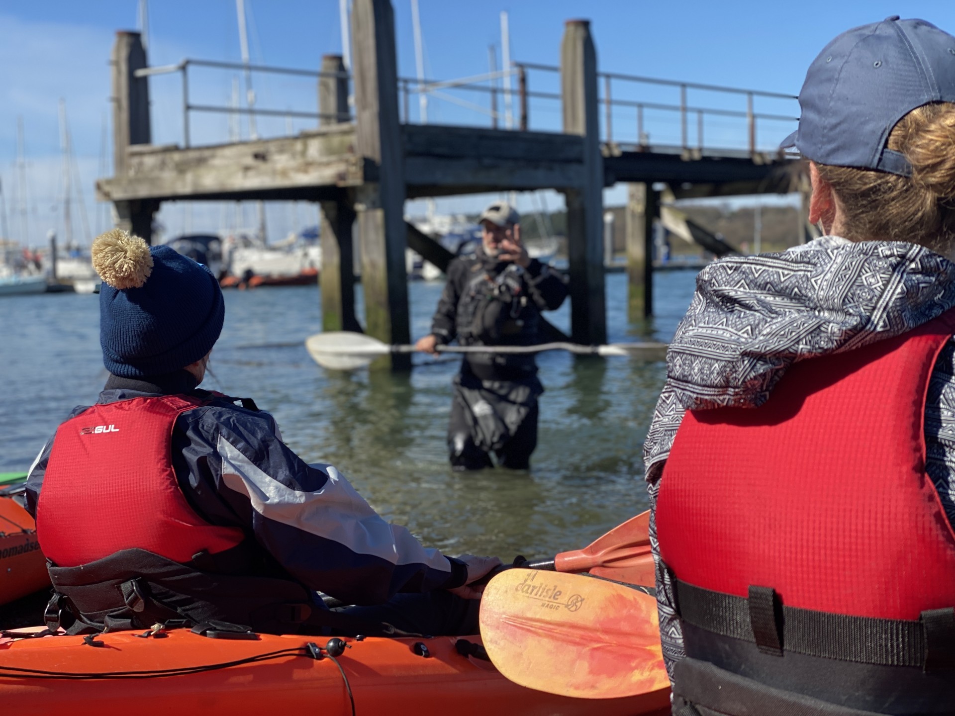 Students on a kayaking course taking instruction at the waters edge.