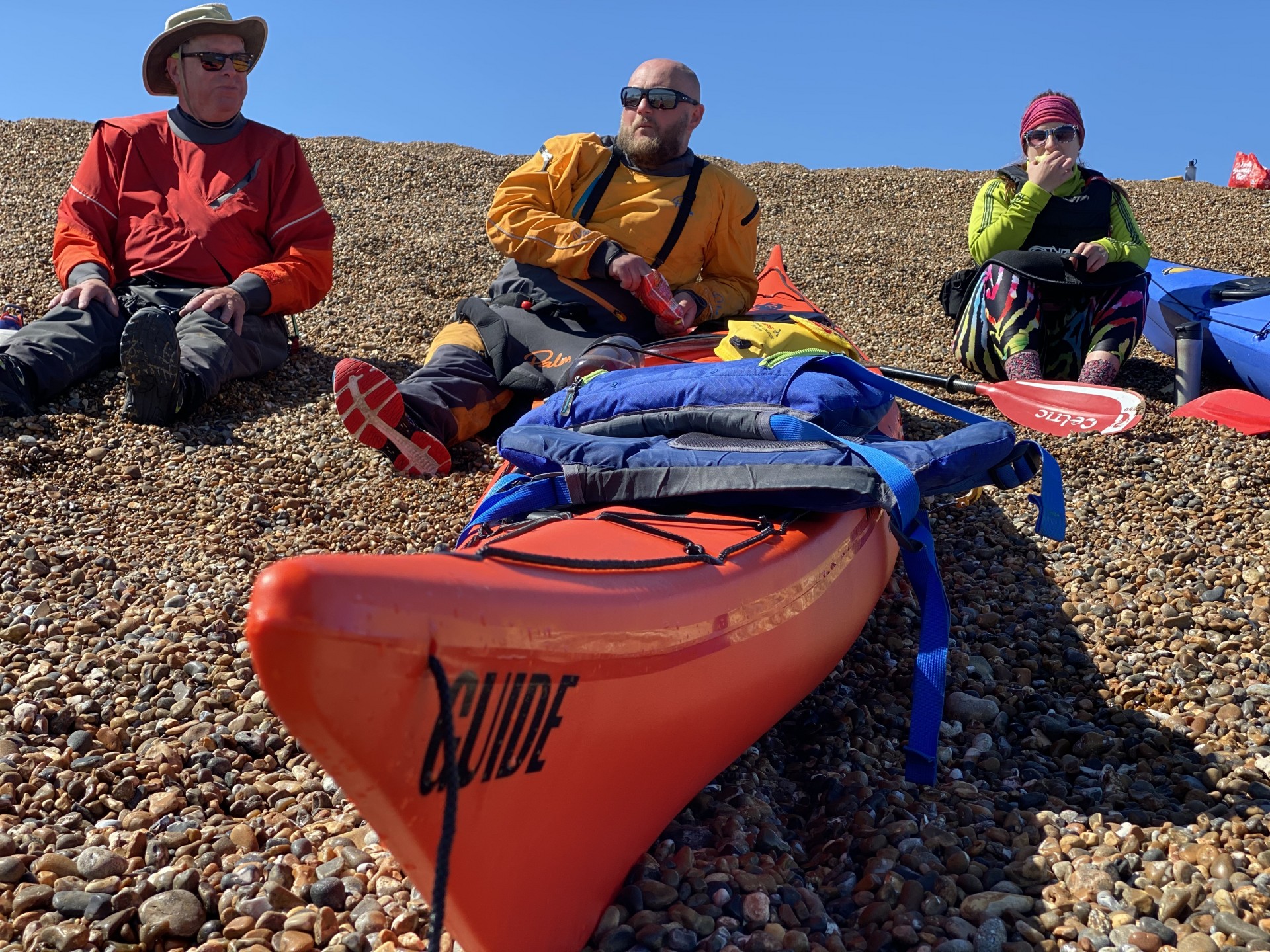 Kayakers having a lunch break on a shingle beach.