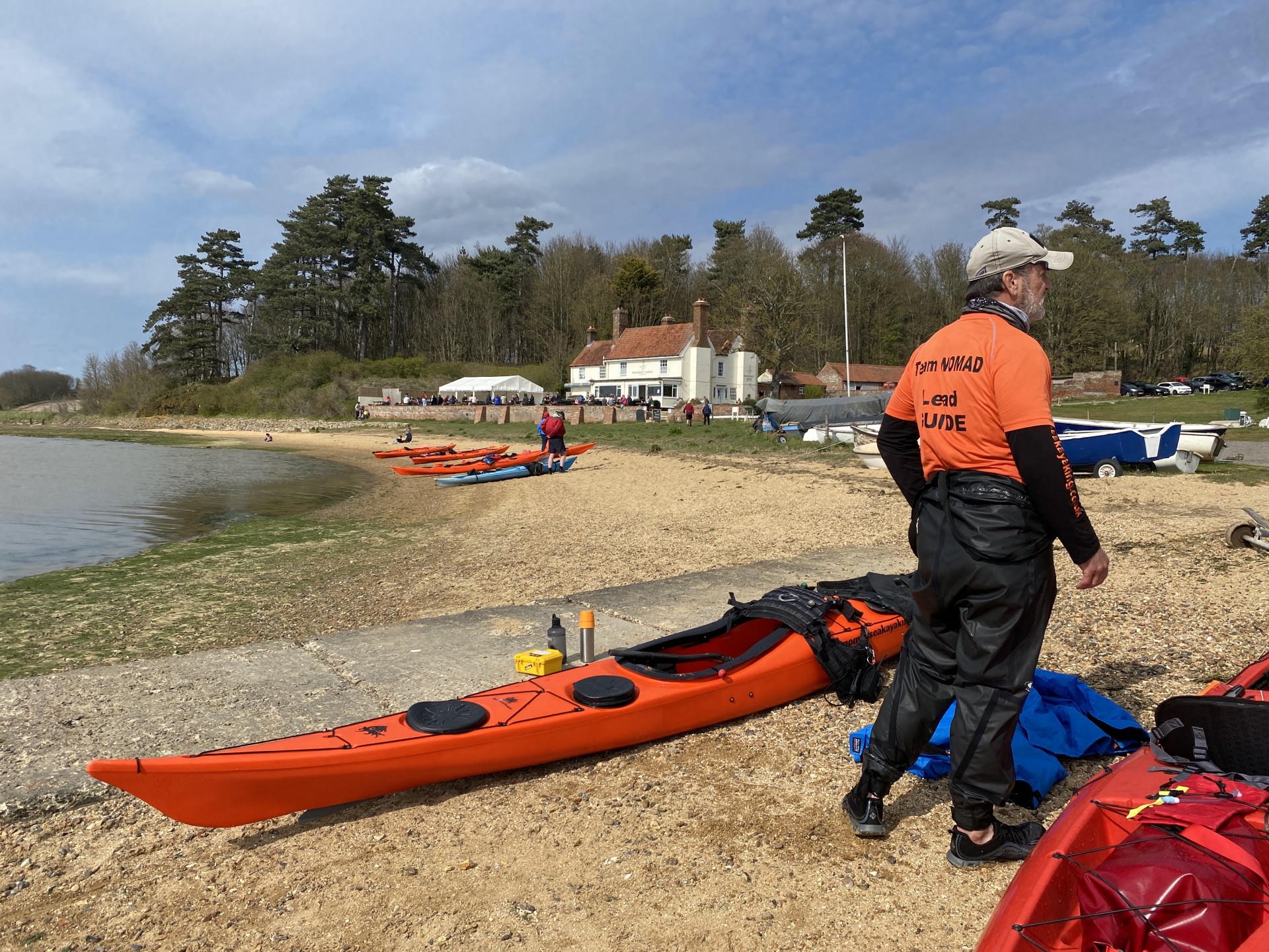 A Guide next to his orange sea kayak on the beach from the Ramsholt arms pub.