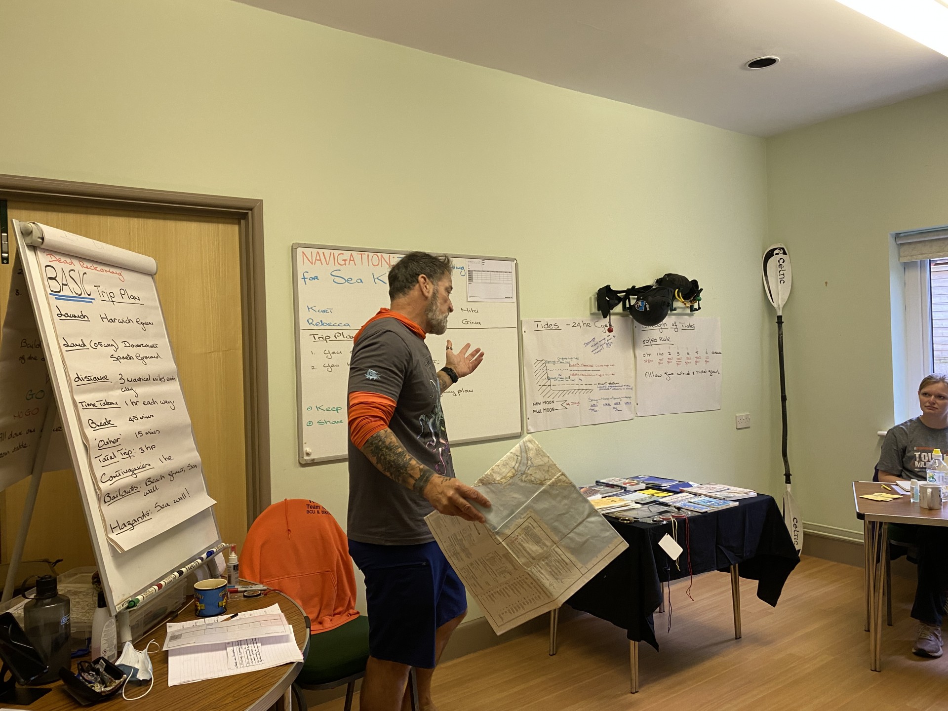 A classroom with whiteboard and flip chart and a paddle in the corner