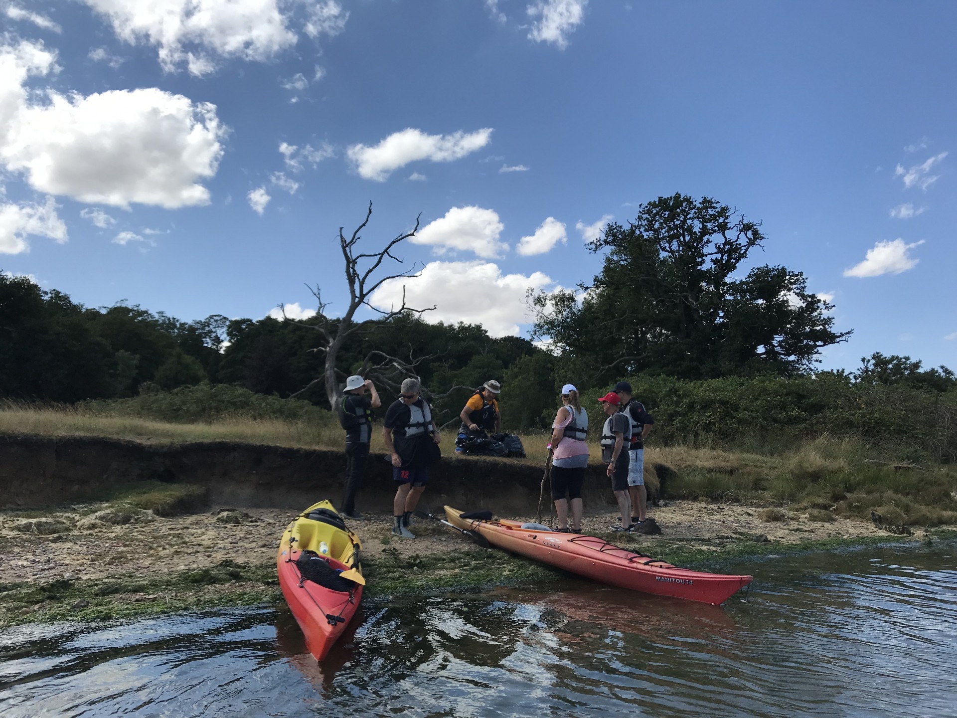 Two kayaks beached wih a small group collecting refuse