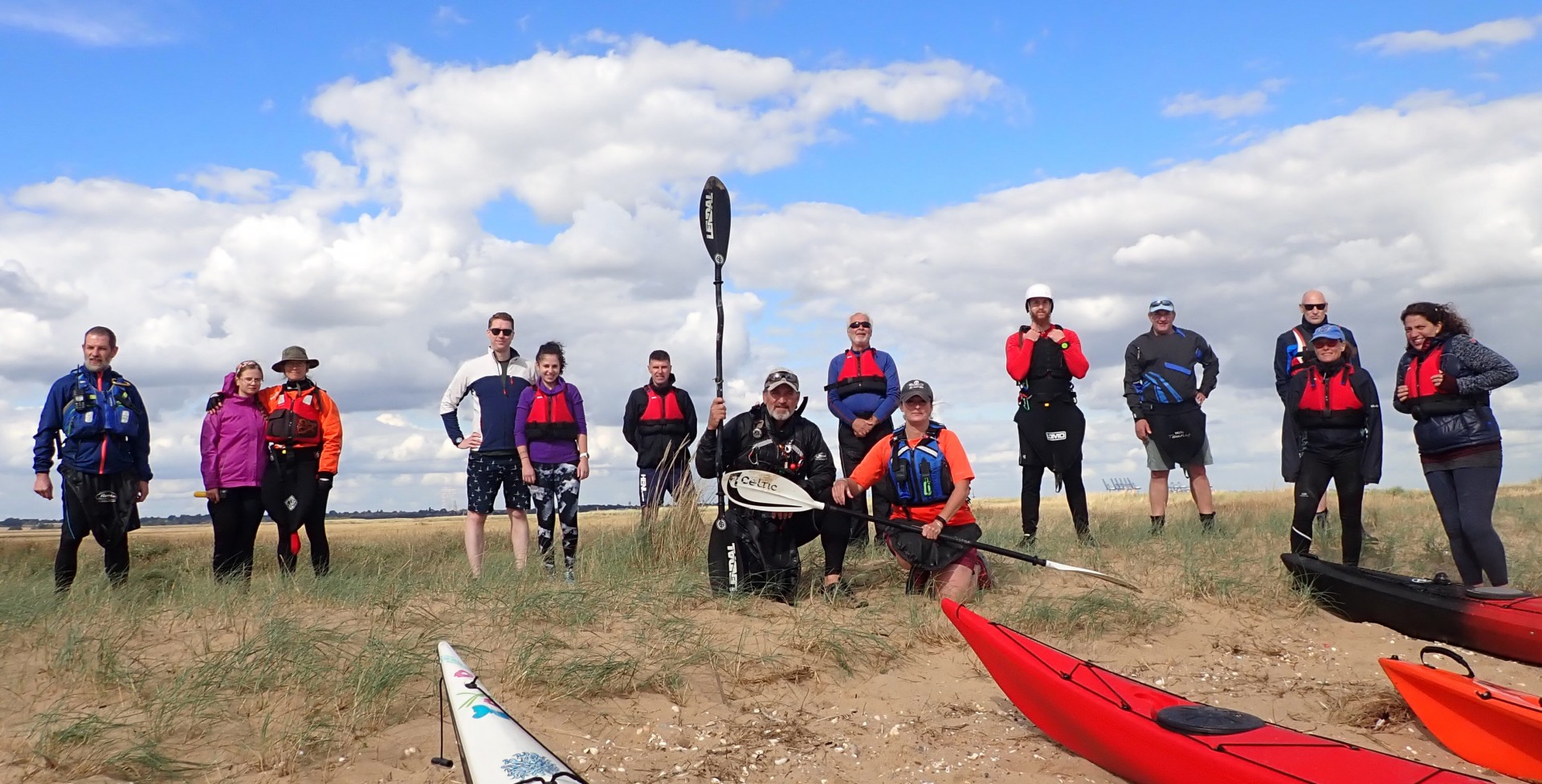 A group off kayakers posing on a beach with their kayaks.