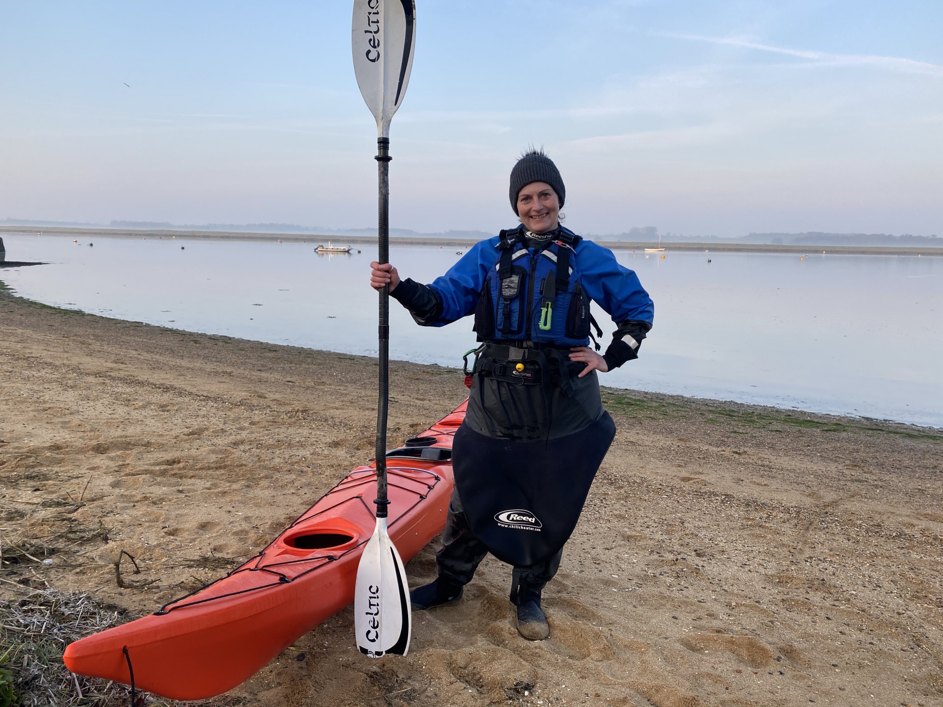 Sea kayaking guide alongside her orange sea kayak.
