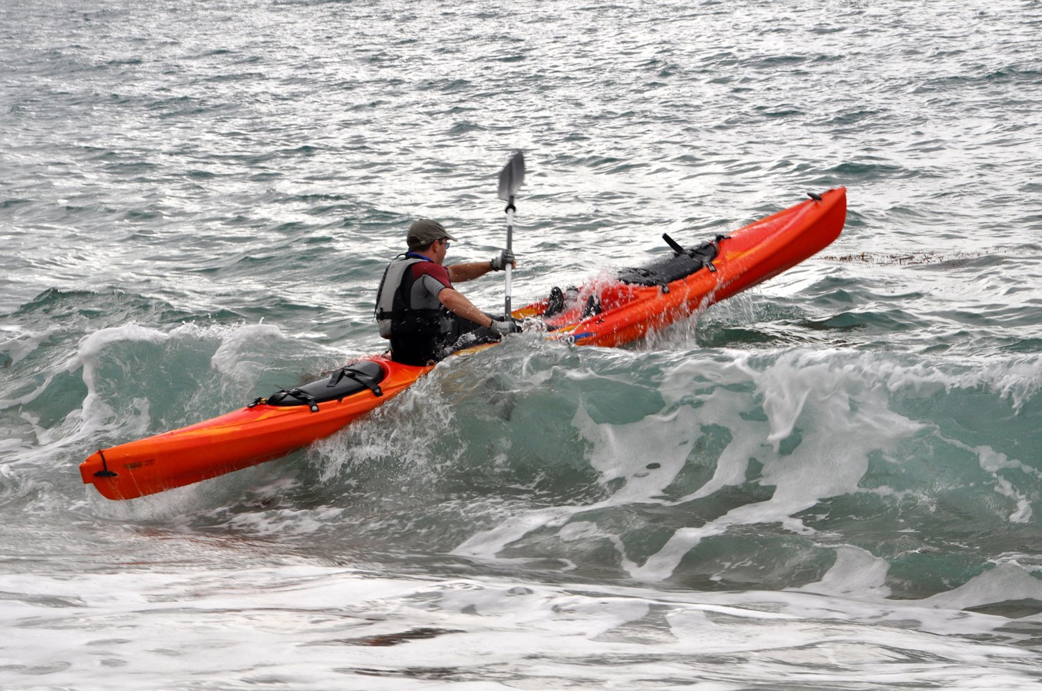 A sit-on-top kayaker breaking through small surf