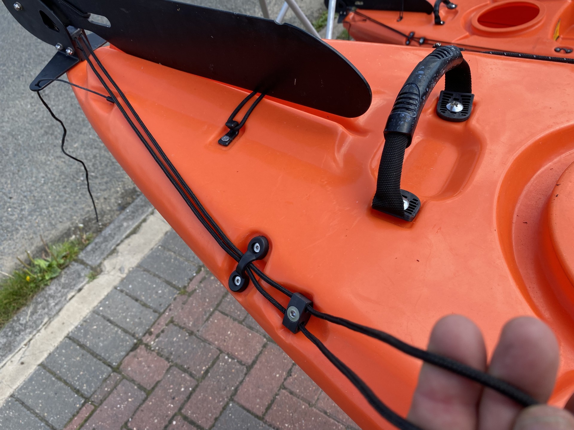 Sit-on-top kayak rudder showing the engagement cables being pulled through the deck guides.