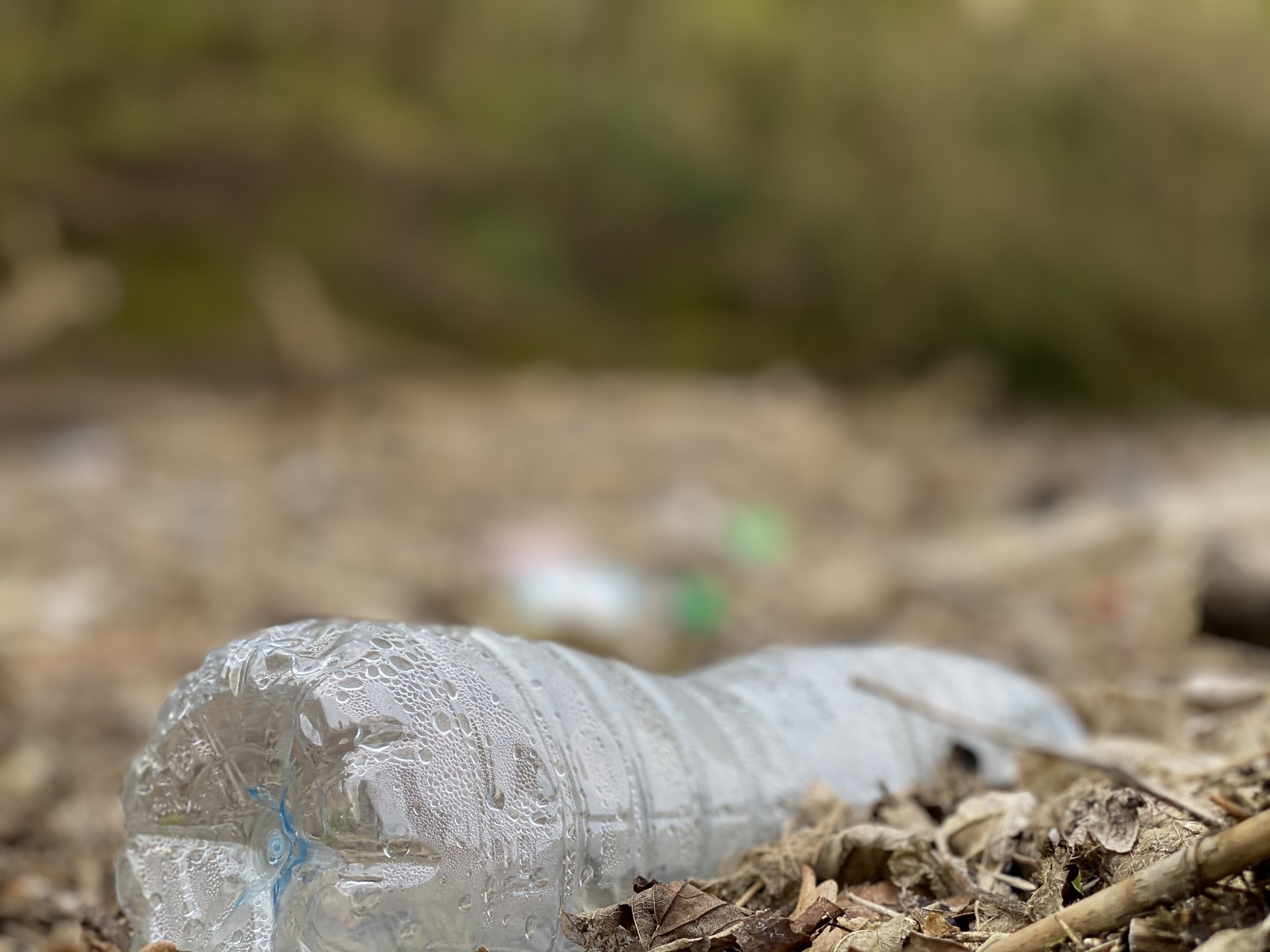 Large clear plastic bottle lying on a beach.
