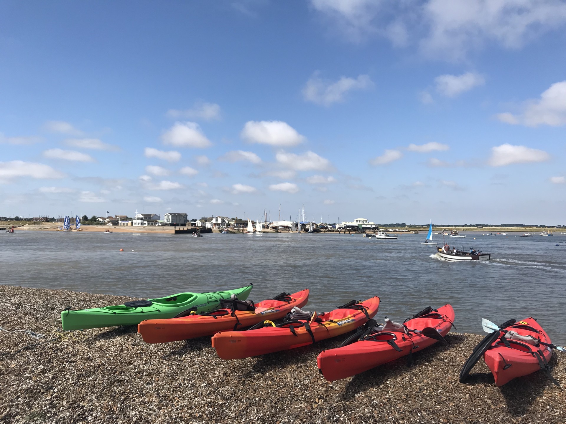Kayaks ready to launch off a shingle beach in Suffolk.