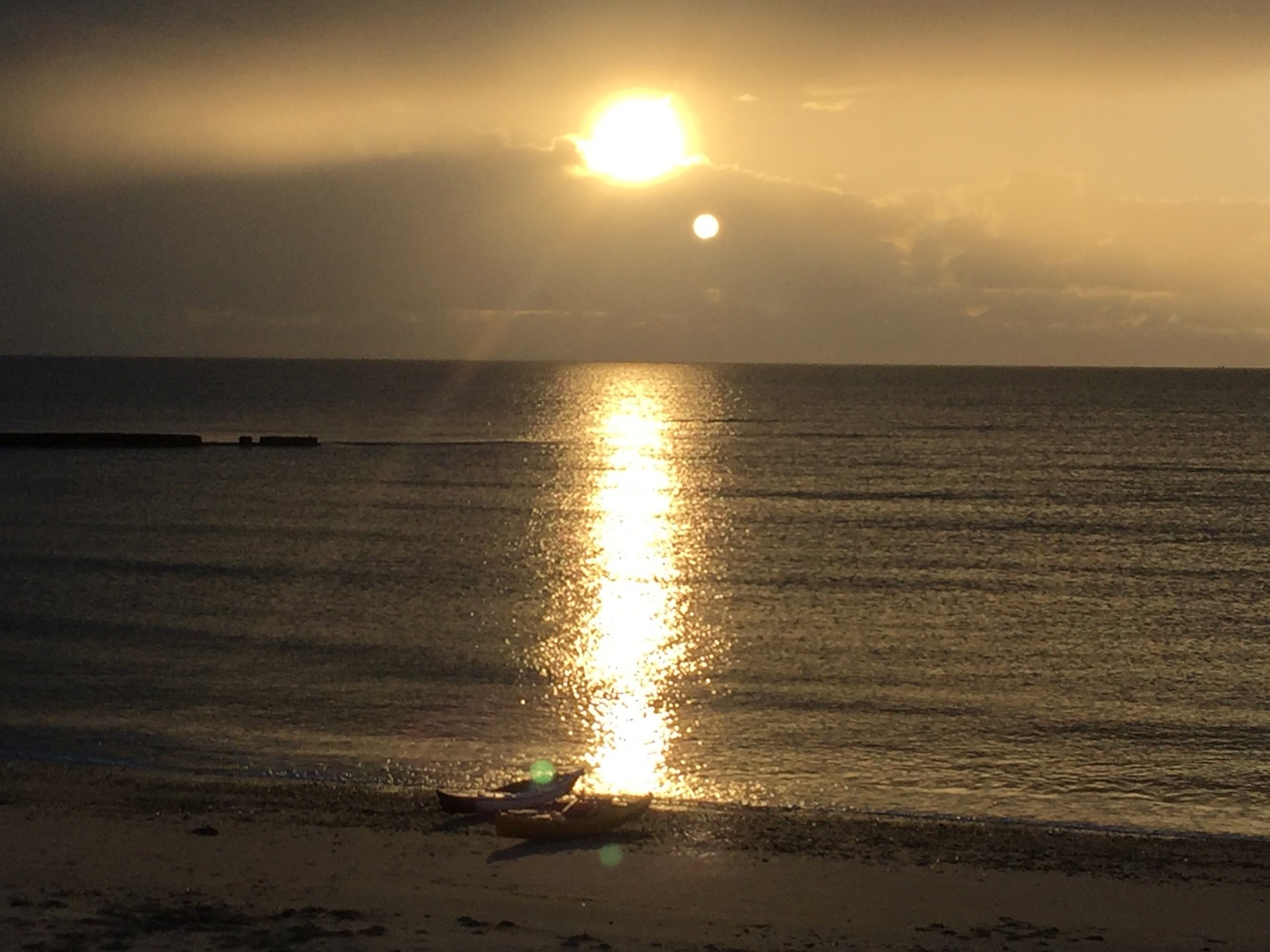 Sunset over the calm seas of East Anglia with two kayaks on the beach, Suffolk night time kayak trip.