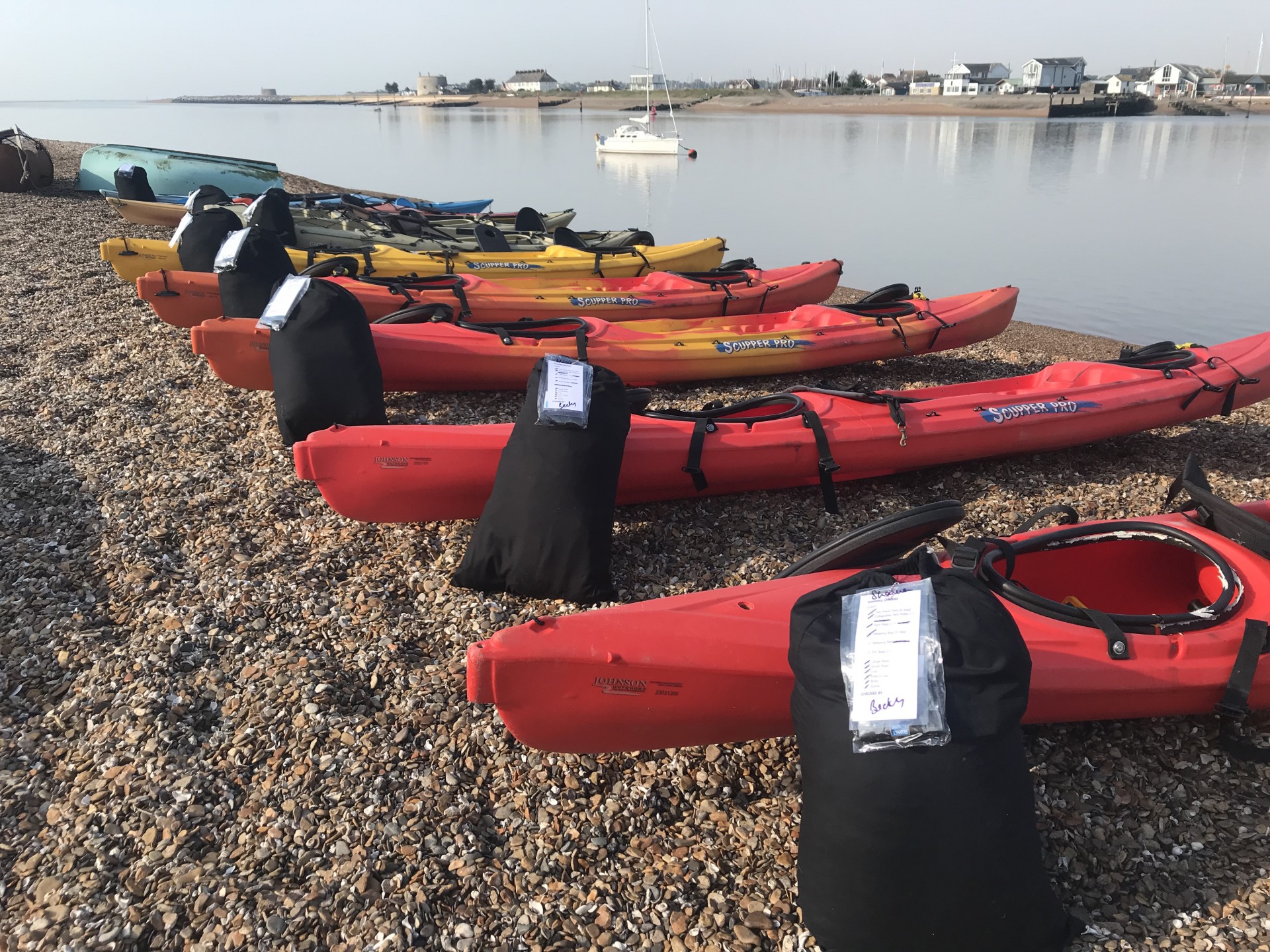 Kayaks neatly lined on a shingle beach in Suffolk.