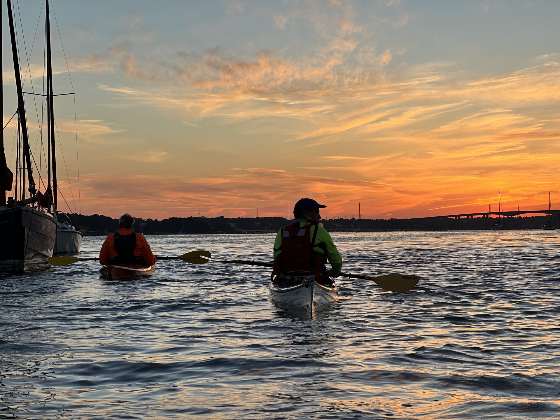 Kayakers drifting past moored yachts on the Orwell estuary with NOMAD Sea Kayaking.