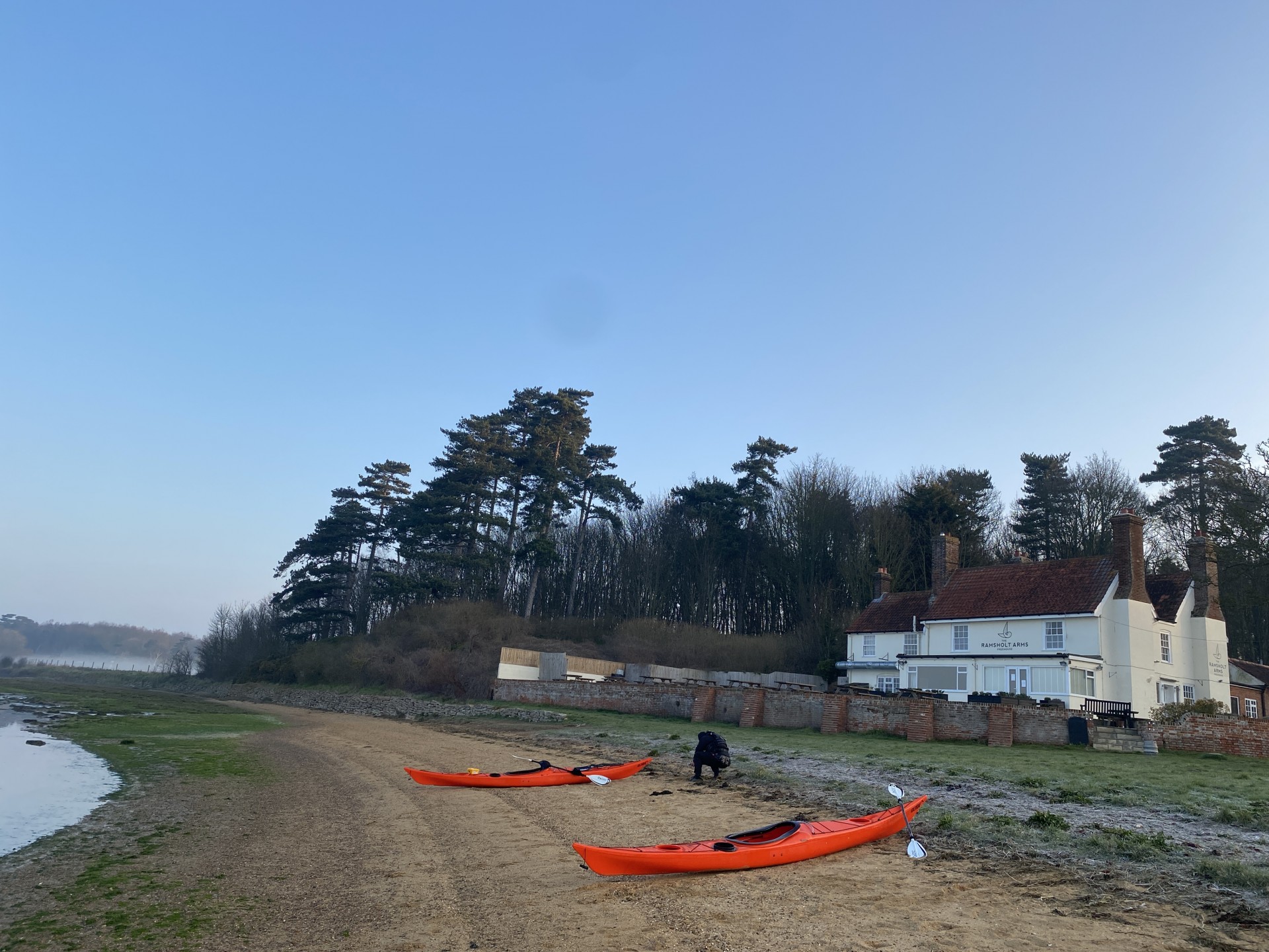 The beach at Ramsholt with two orange sea kayaks and a blue sky.