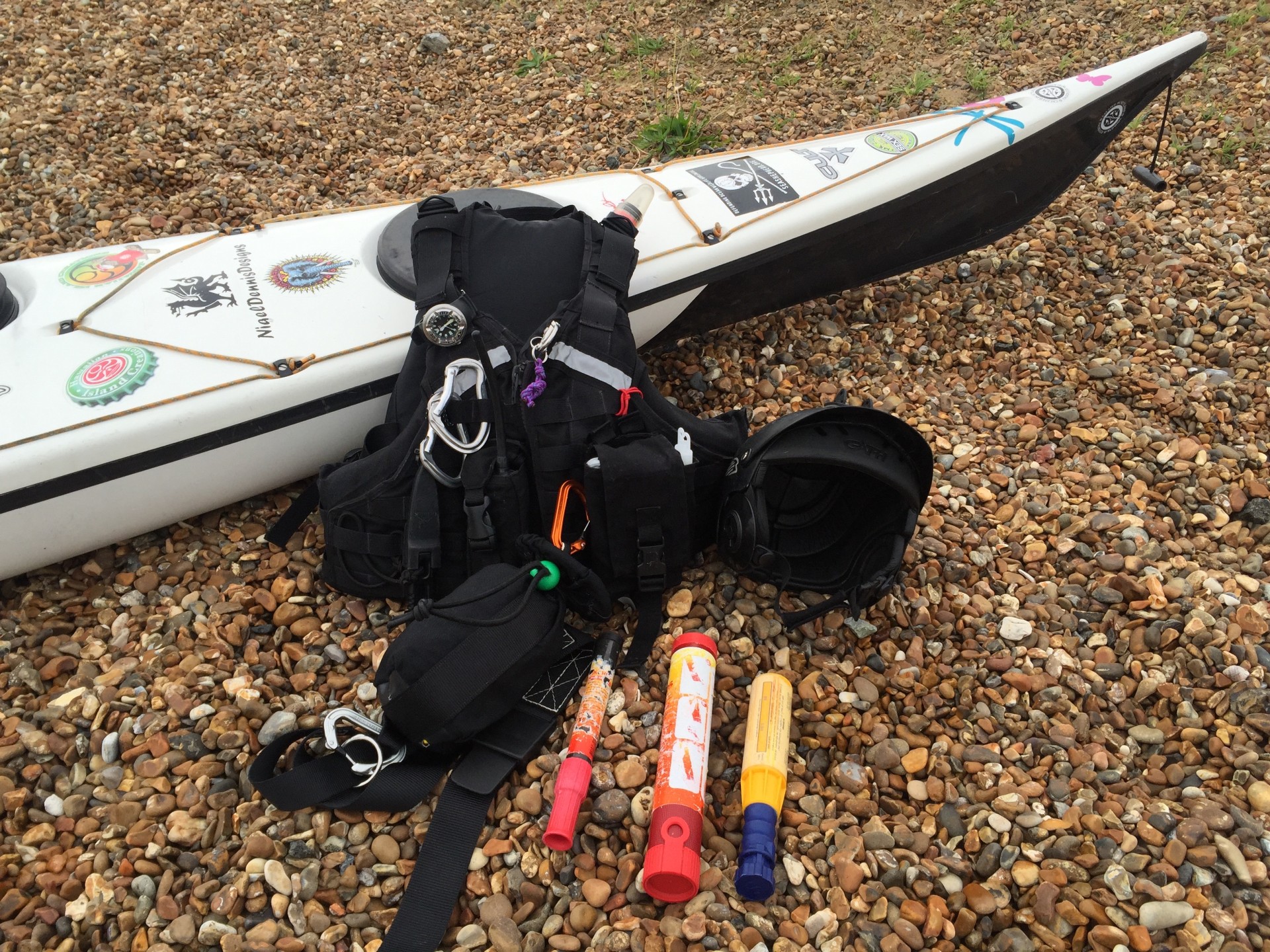 Safety equipment for sea kayakers laid out on a shingle beach.