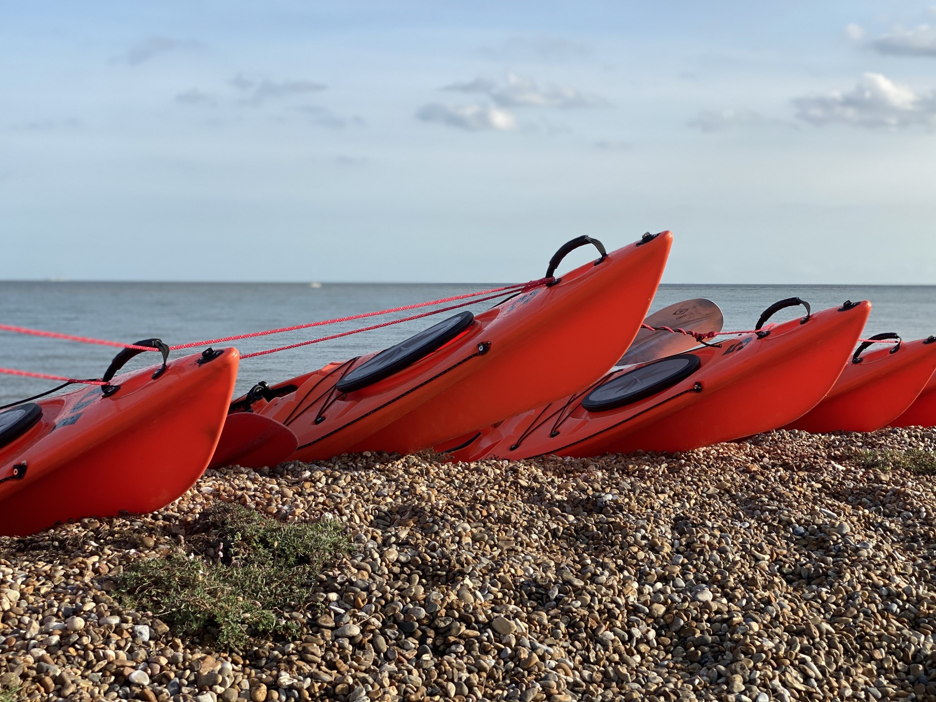 Orange kayaks on the beach ready for launch.