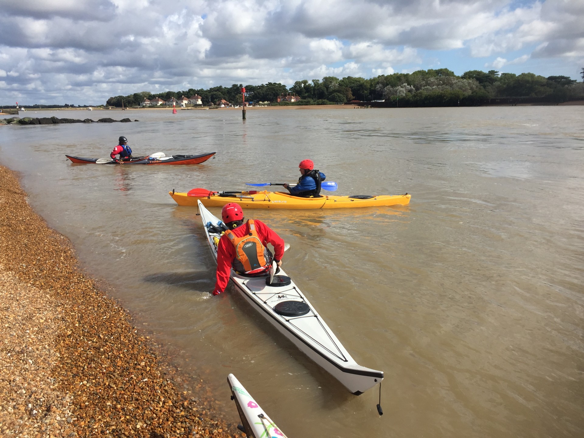 Sea kayakers launching in flat calm tidal conditions at the mouth of the Deben estuary.