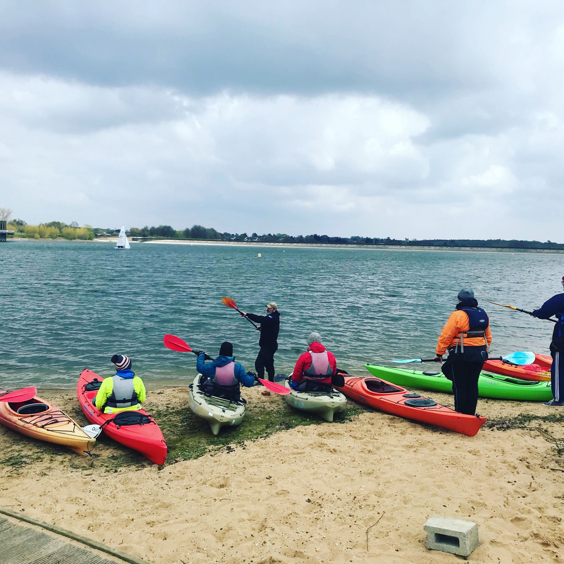 A kayaking coach instructing his students on the beach.