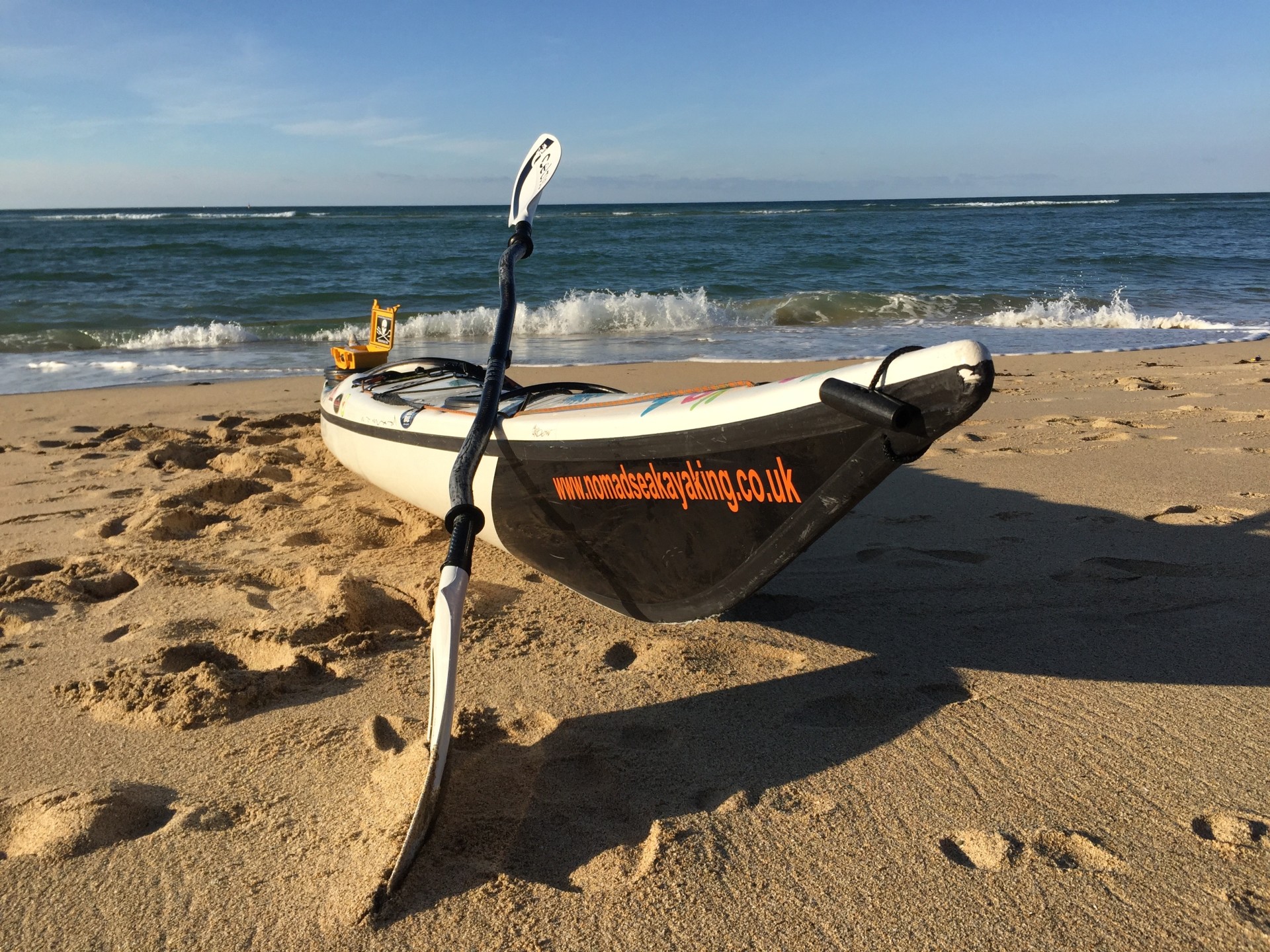Sea kayak and paddle on a sandy beach with NOMAD Sea Kayaking.