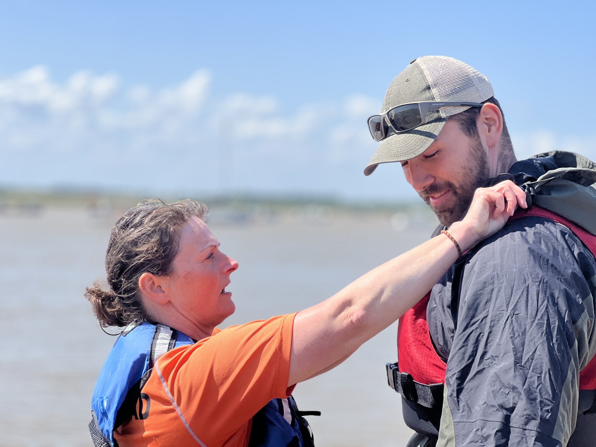 Guide adjusts a guests buoyancy aid before sea kayaking.