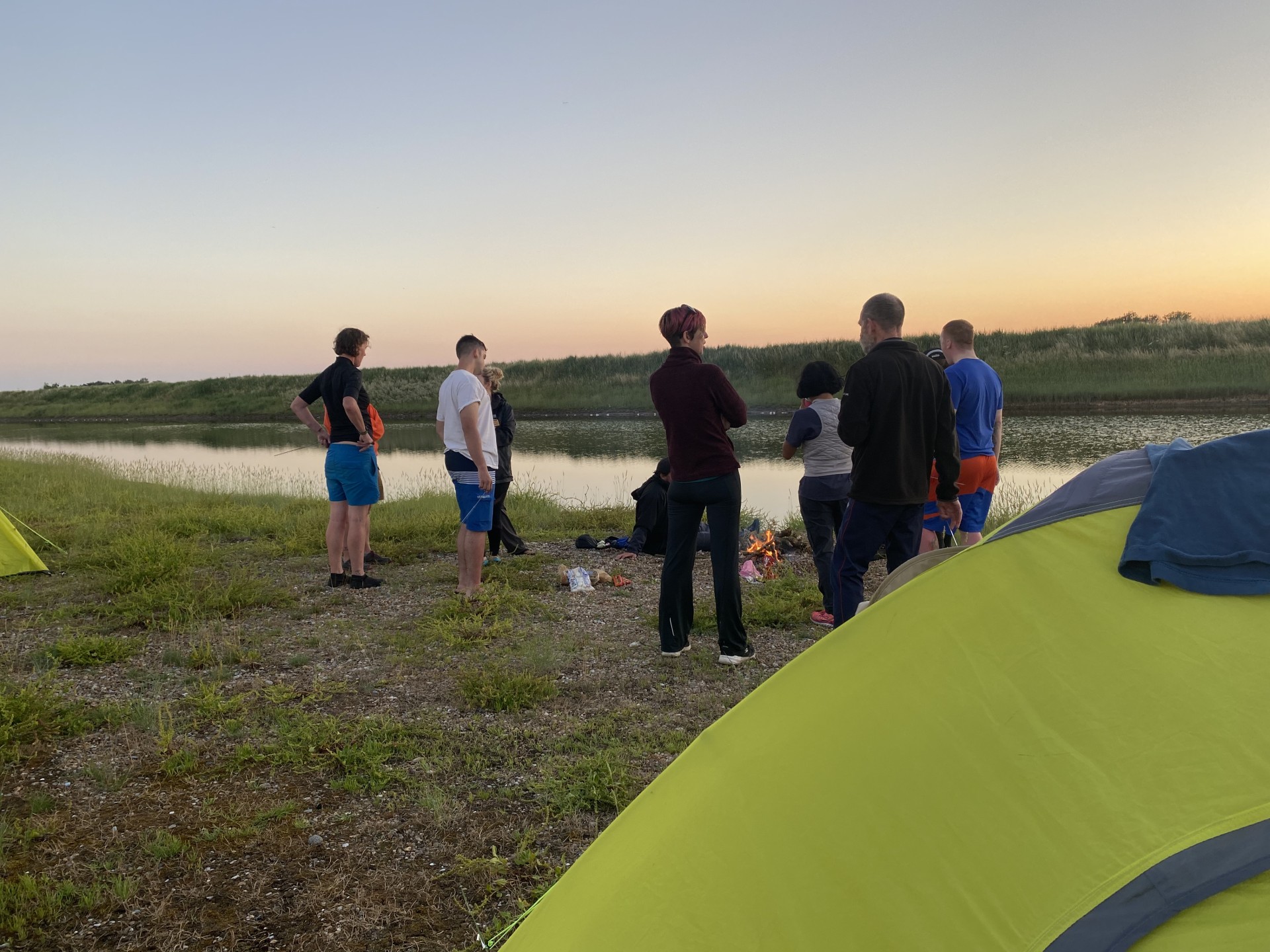 Wild camping in Suffolk around the evening camp fire, sun setting in the background.