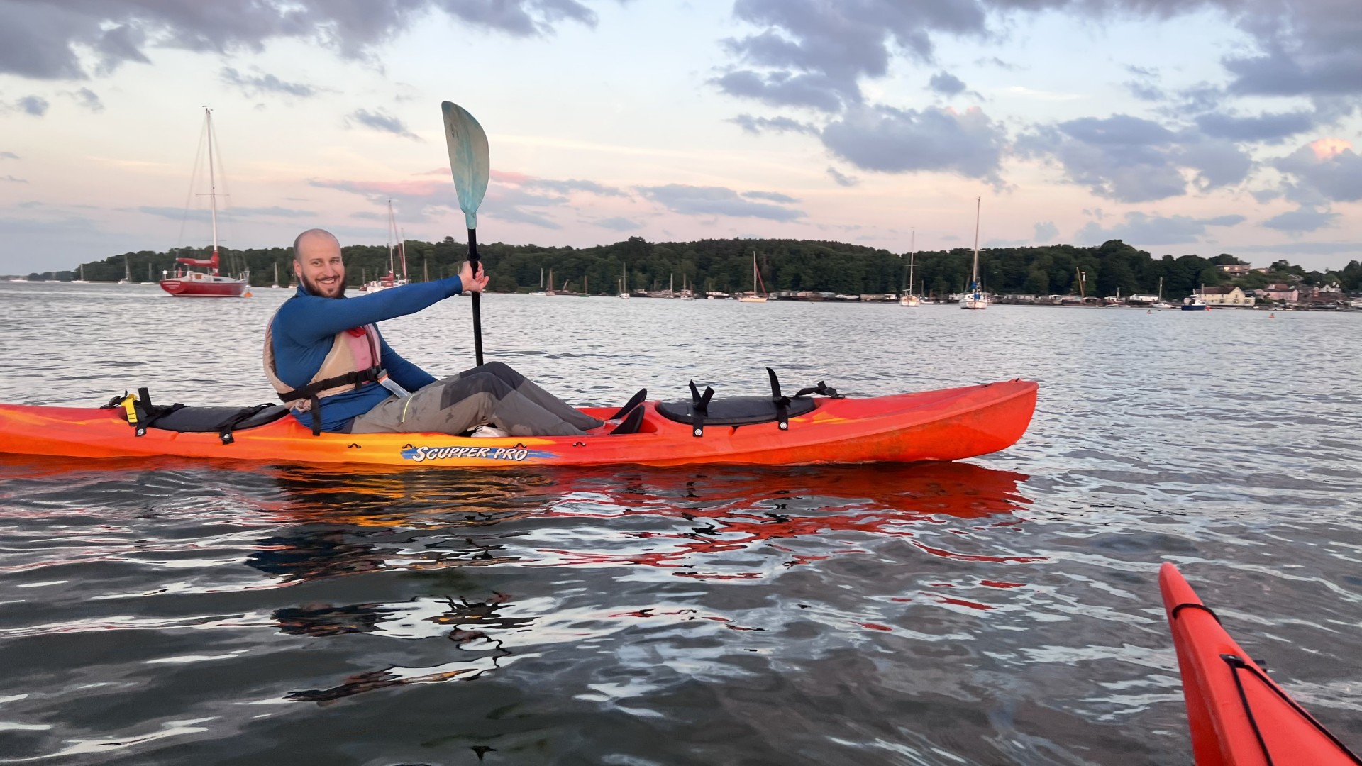 Sea kayaker on a red sit-on-top kayak with NOMAD Sea Kayaking.