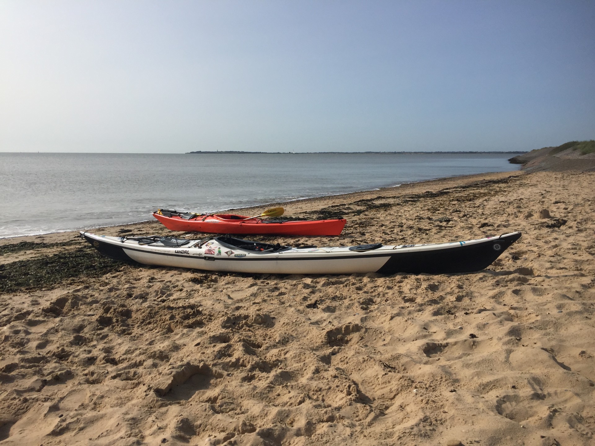 Sea kayaks on a beautiful sandy beach with NOMAD Sea Kayaking.