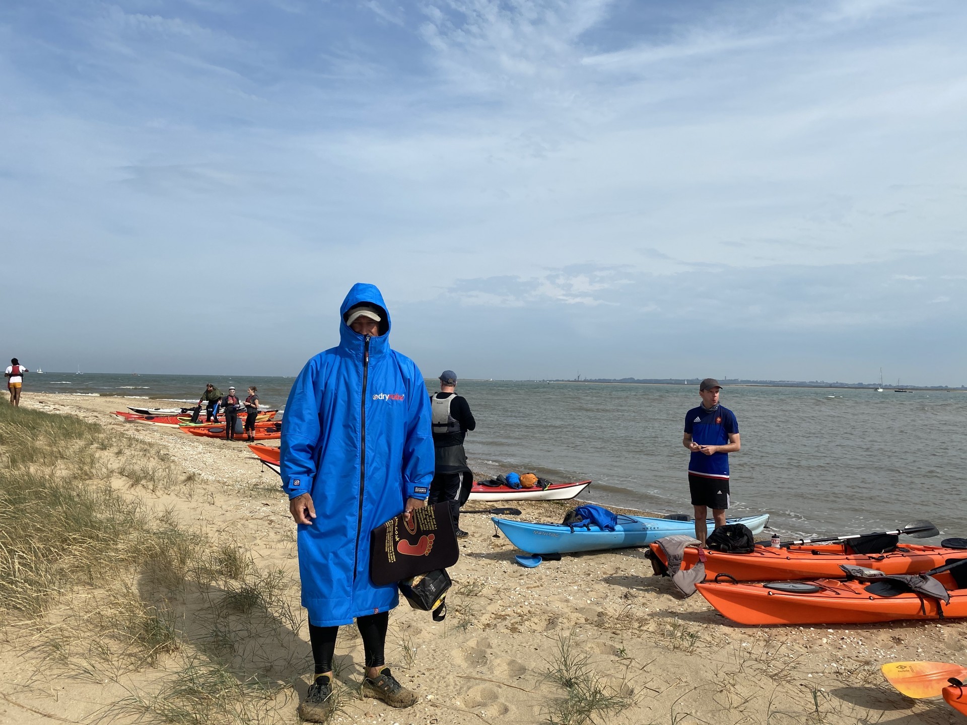 A guide in warm clothes stands on a beautiful sandy beach on a clear day.