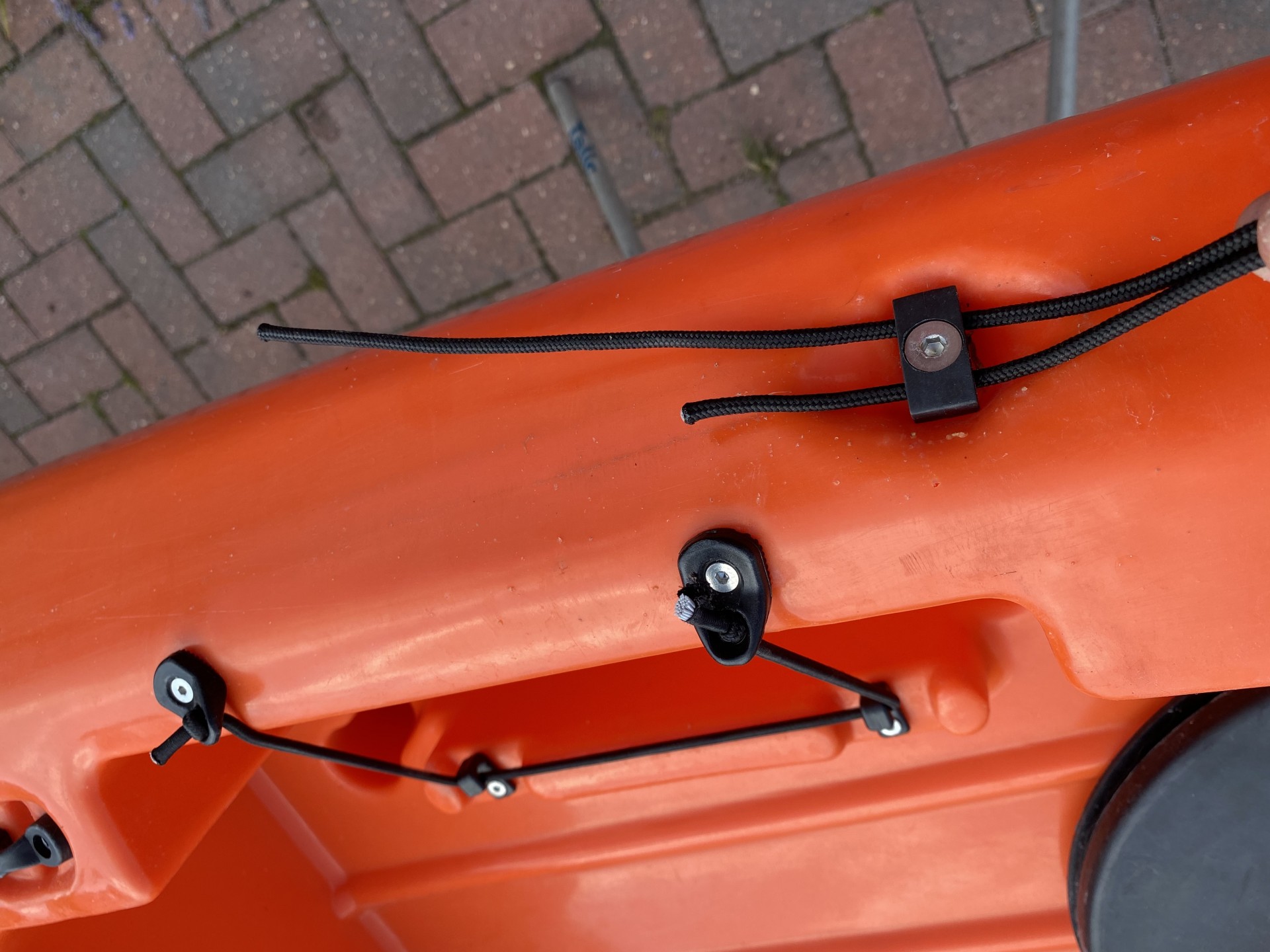 Sit-on-top kayak rudder engagement cable being inserted through deck guides.