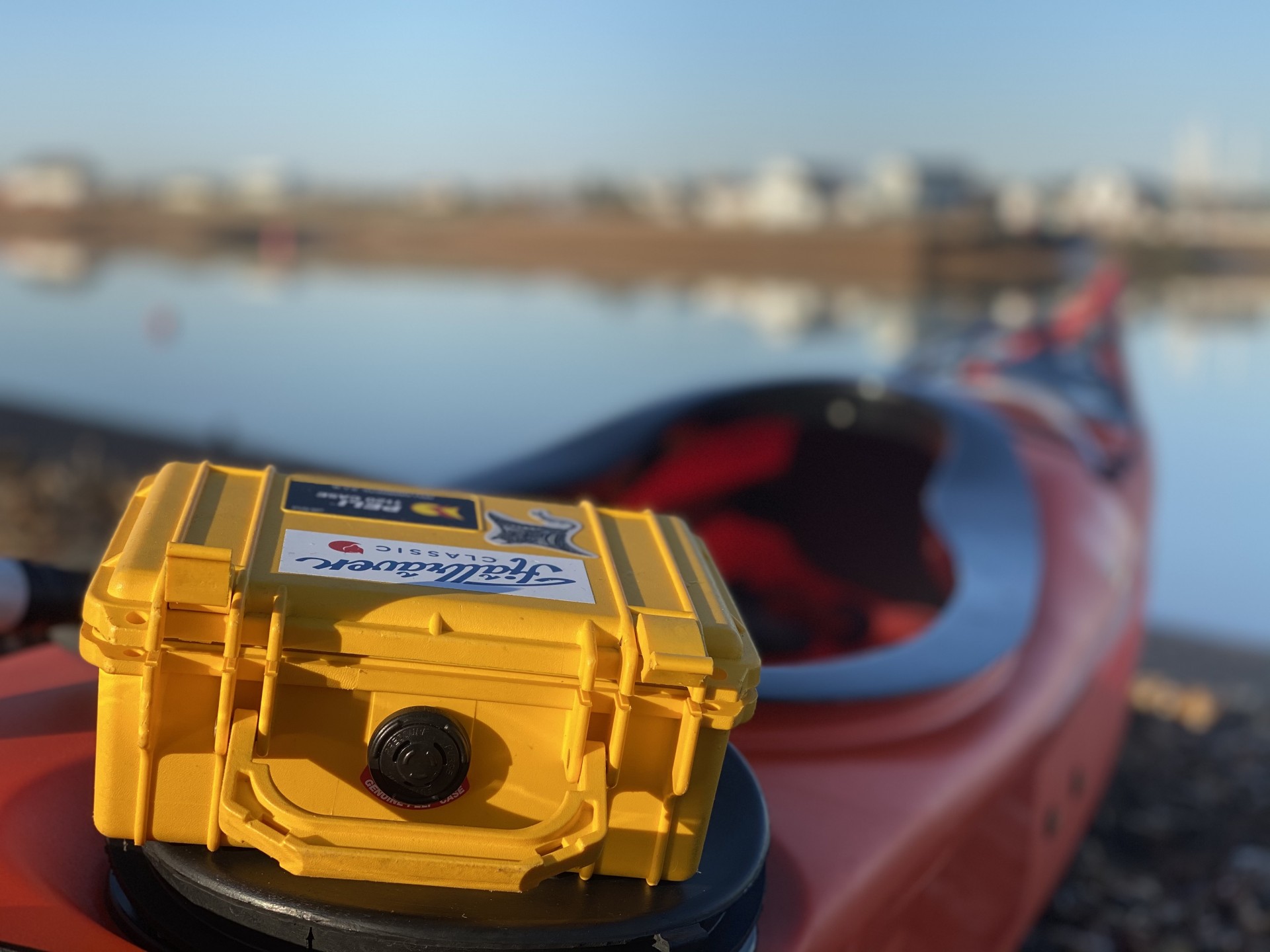 A yellow Peli case on a sea kayak with the sea in the background.