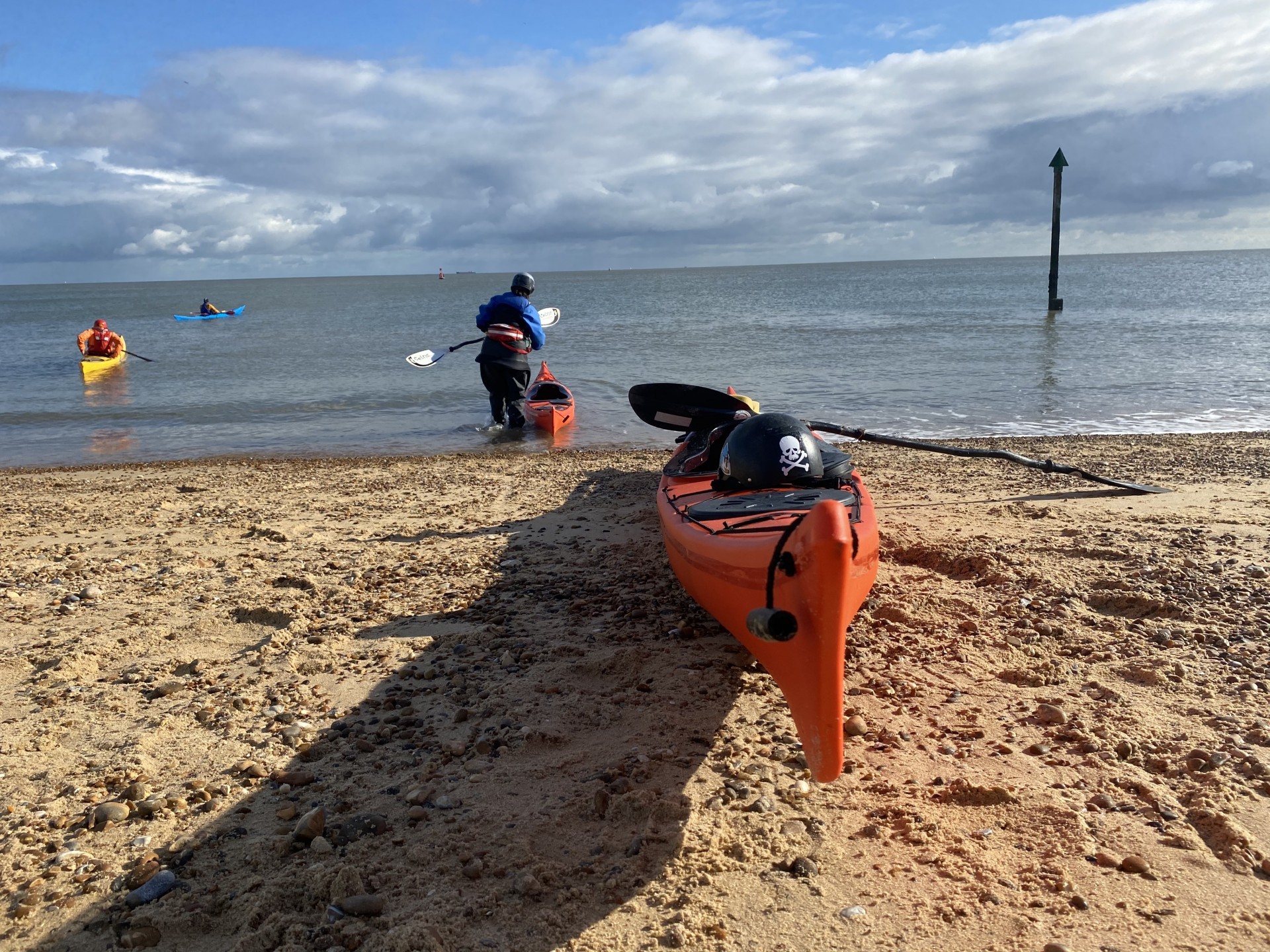 Sea kayakers launching in flat, calm sea conditions