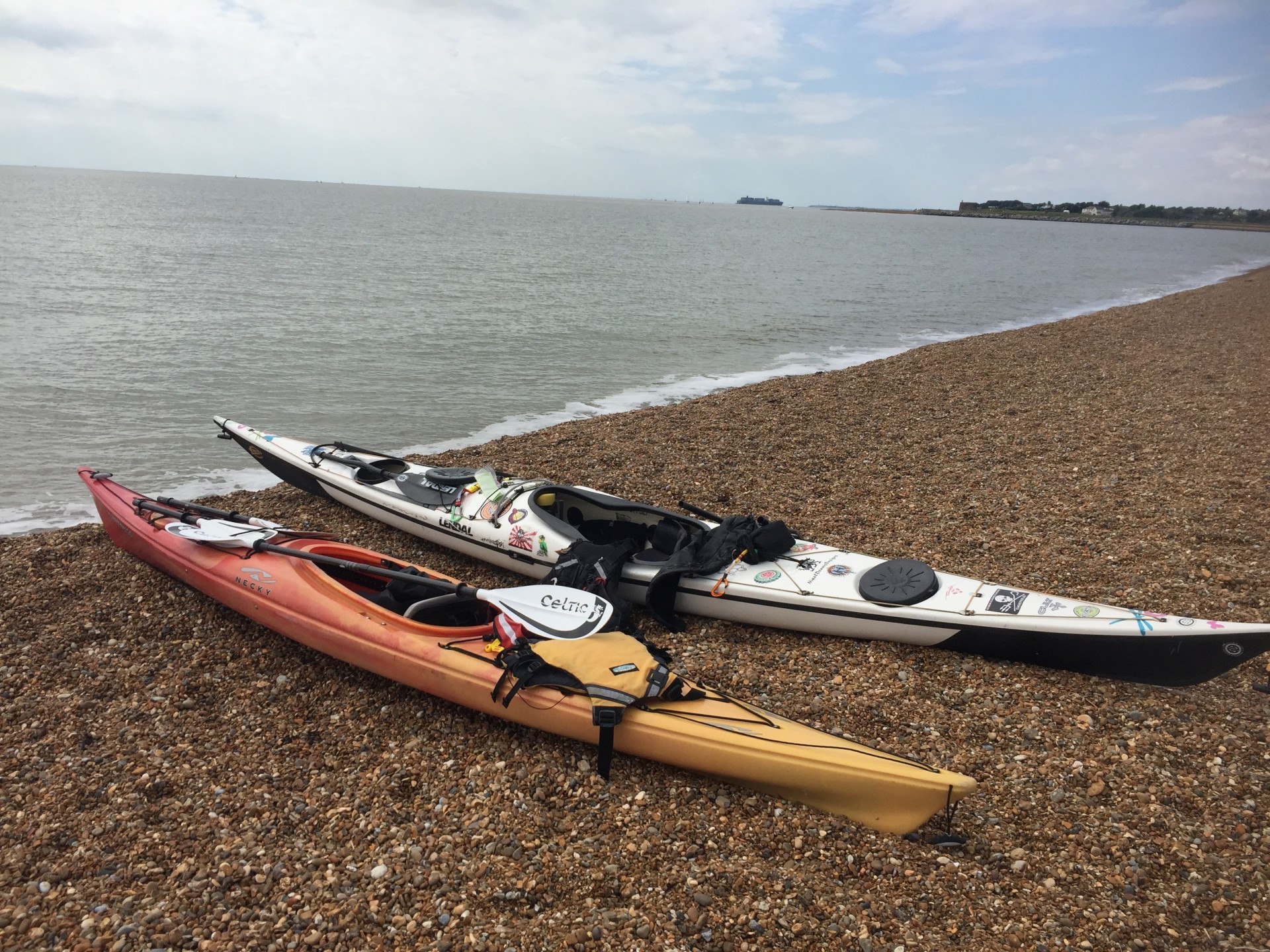 Two sea kayaks on a beach with the sea in the background