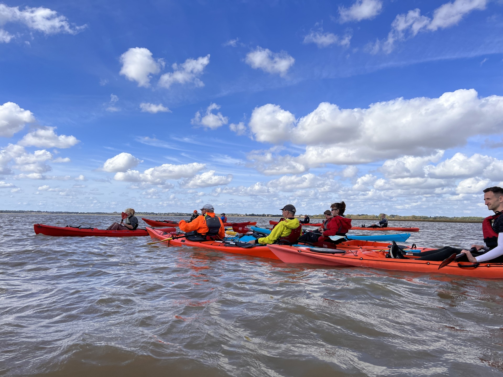 Sea kayak group on the water under blue skies.