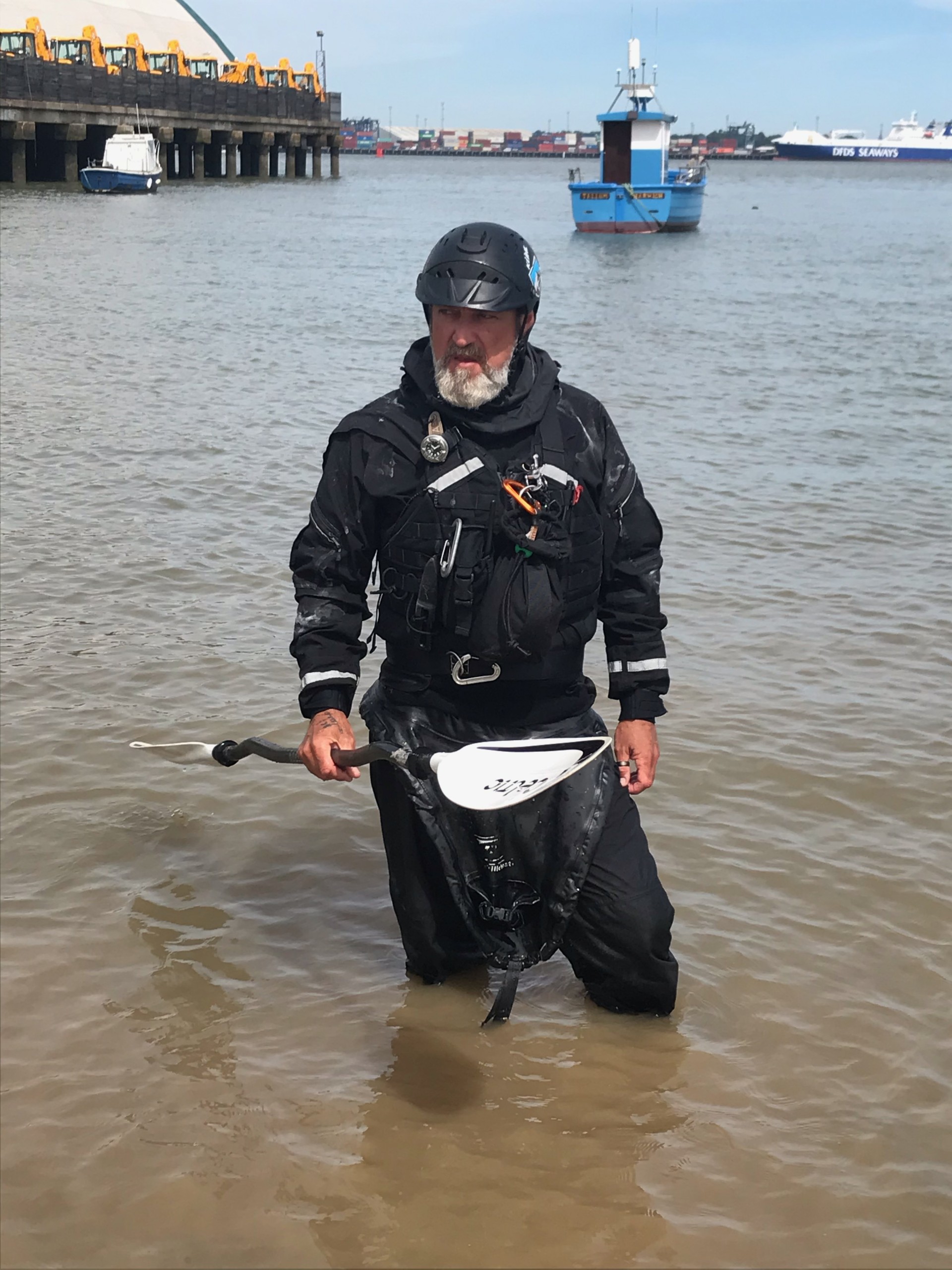 Sea kayaker in a black drysuit with NOMAD Sea Kayaking.