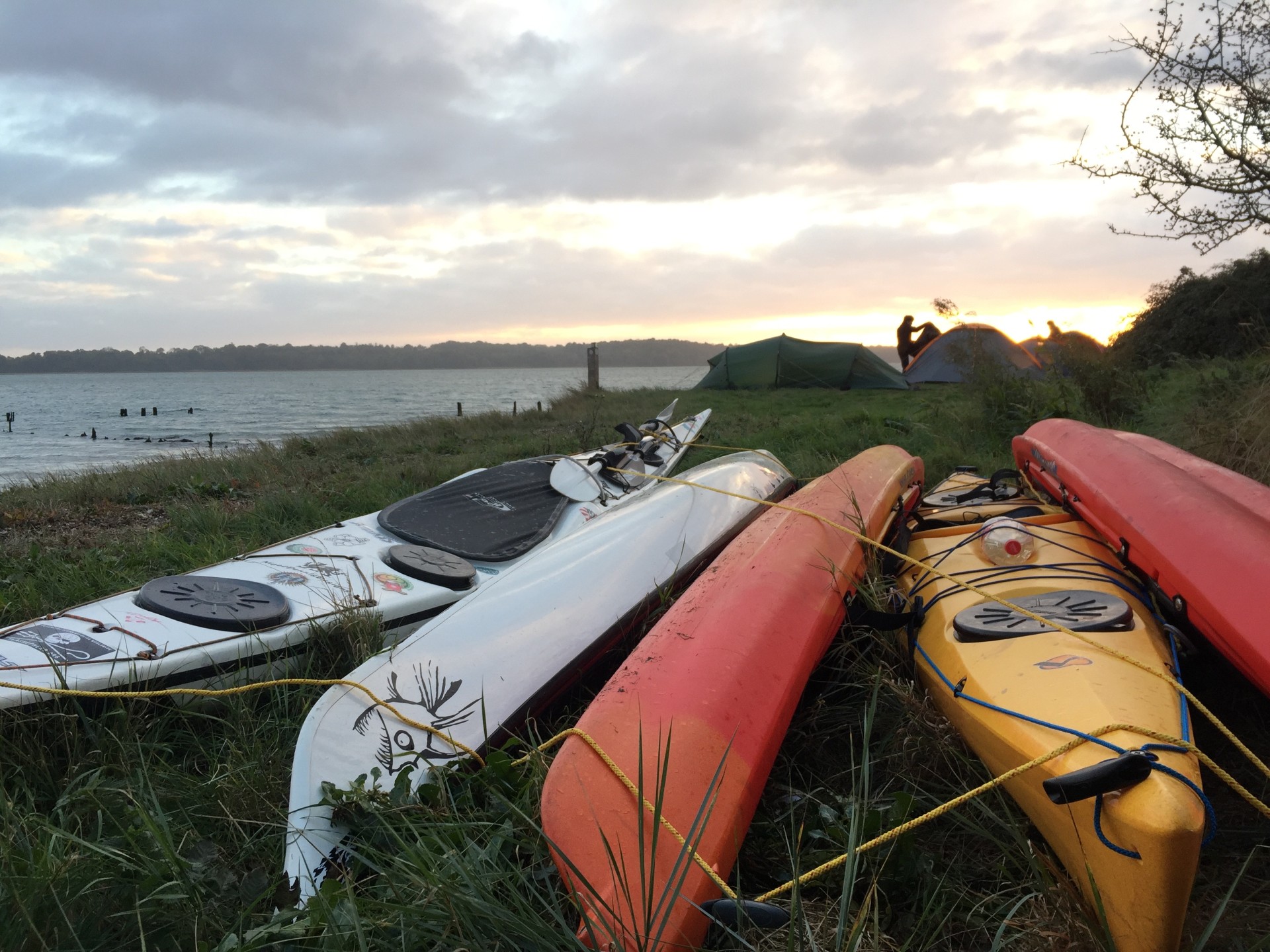 A selection of sea kayaks tethered for a nights wild camping with NOMAD Sea Kayaking.
