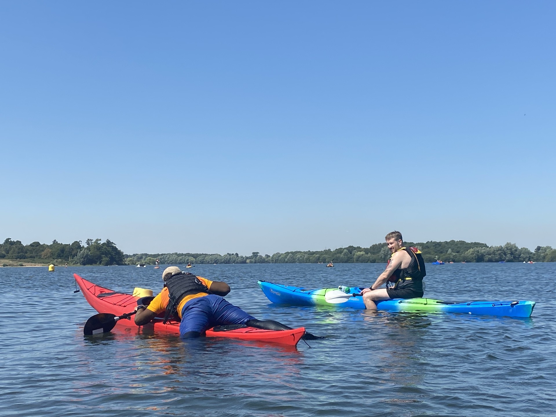 Kayakers straddling their sea kayaks in calm water.