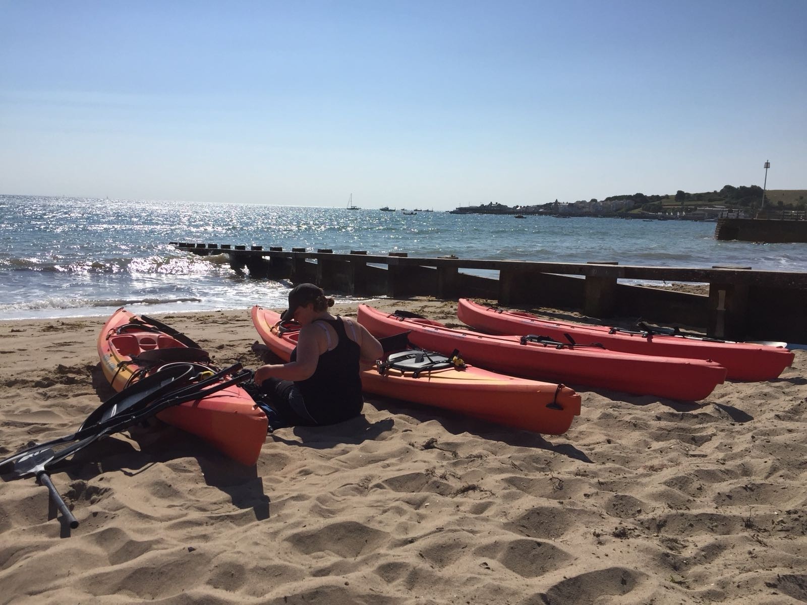 Kayaks on a beautiful sandy beach with bright blue sky and sunshine on the blue sea