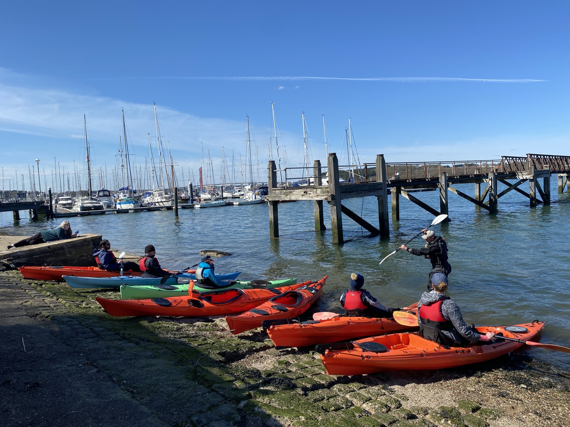 Coach standing in front of group teaching students sea kayaking with NOMAD Sea Kayaking.