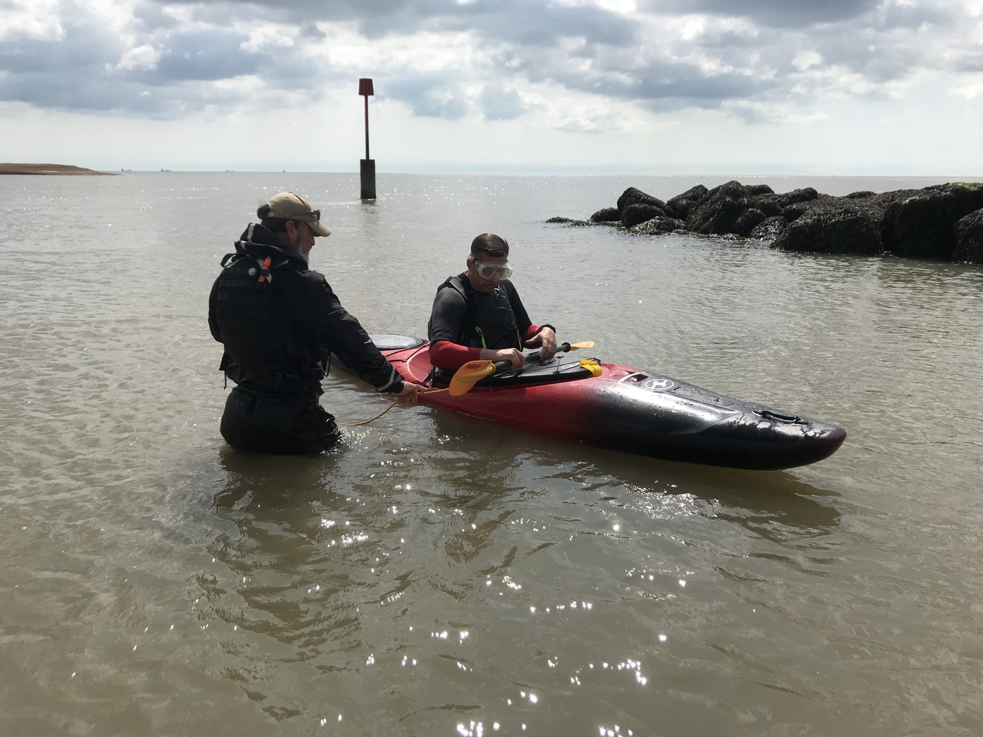 /storage/Coach standing in water teaching a kayaker to roll his kayak.